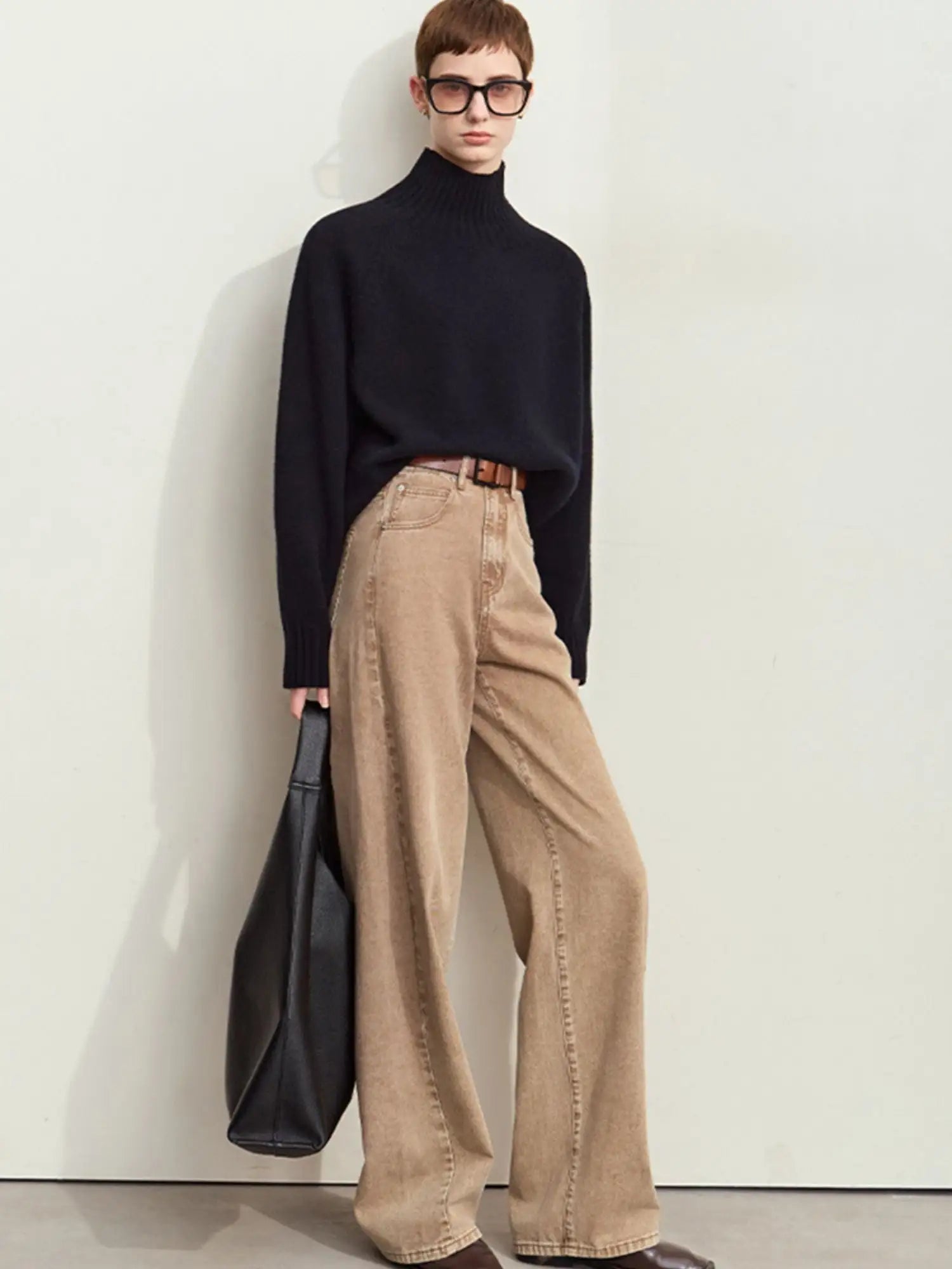 Woman in a black sweater and brown jeans.