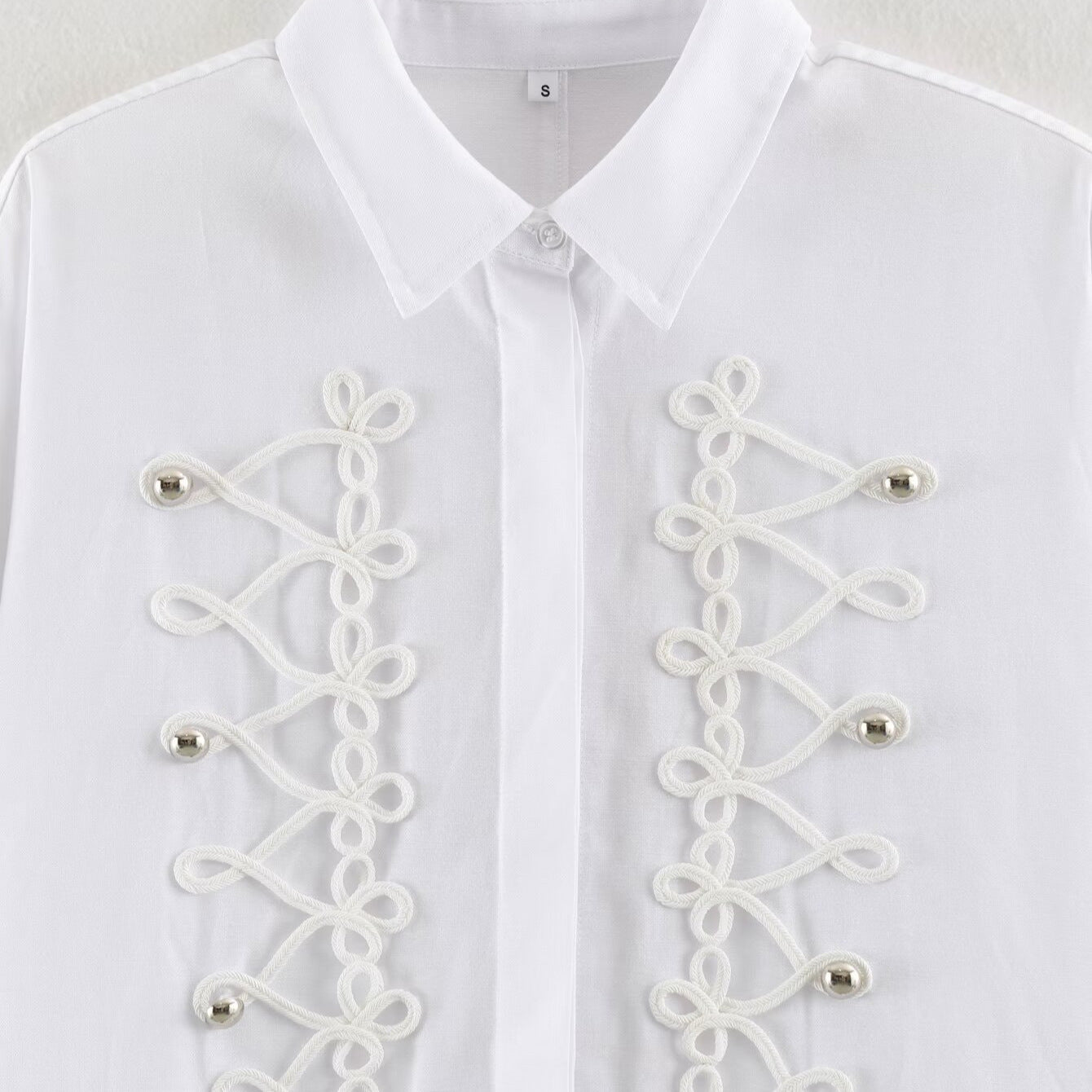 Women's blouse with long sleeves and decorative frog jewelry as well as concealed button placket