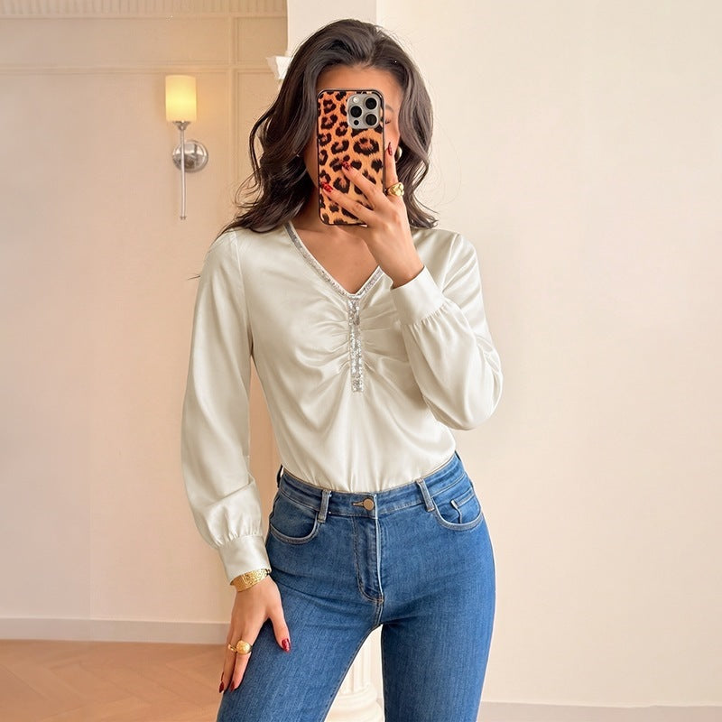 Women's satin blouse with V-neck, gathered front section and decorative ribbon.