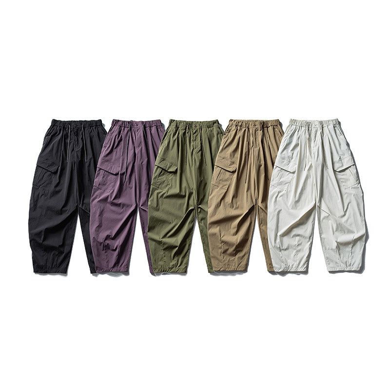 Men's wide ripstop cargo pants in balloon cut with drawstring waistband, oversized flap pockets, and elastic ankle cuffs.