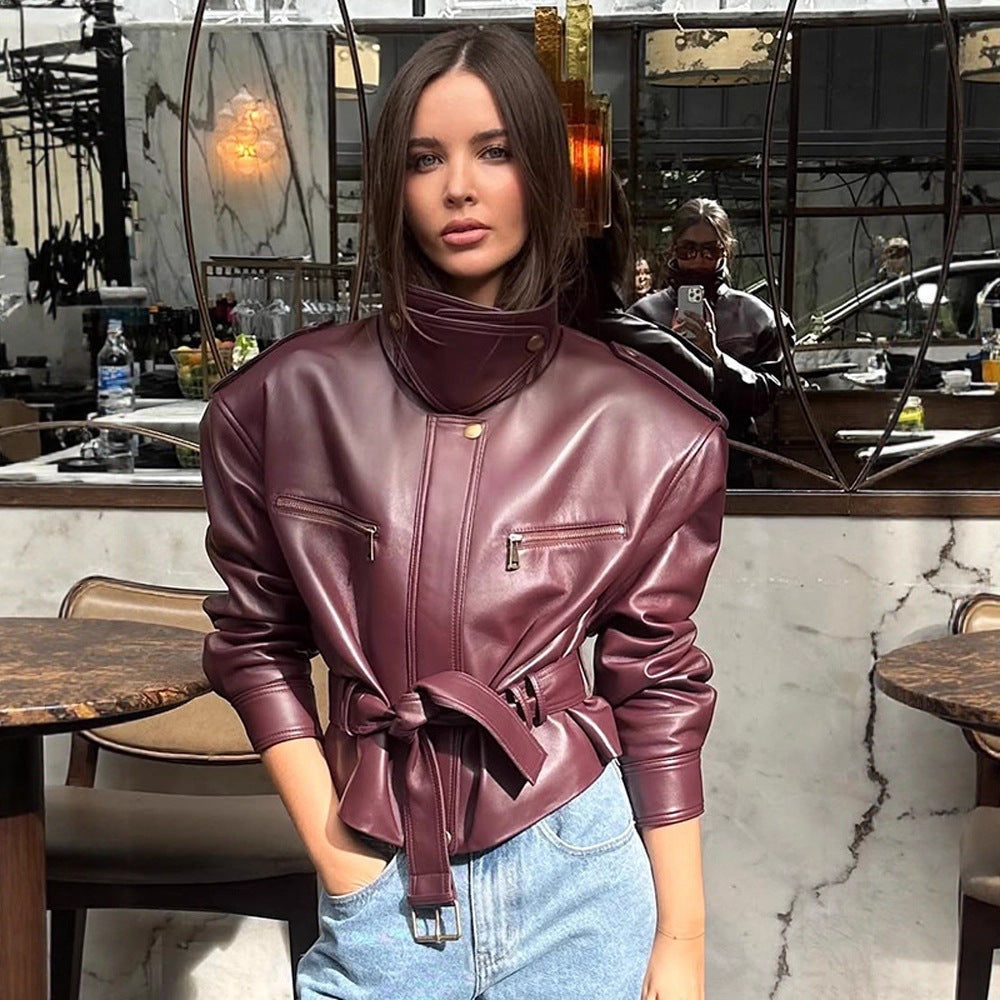 Women's short jacket made of faux leather with a high stand-up collar, fitted tie belt, and prominent shoulder pads Chichicherry