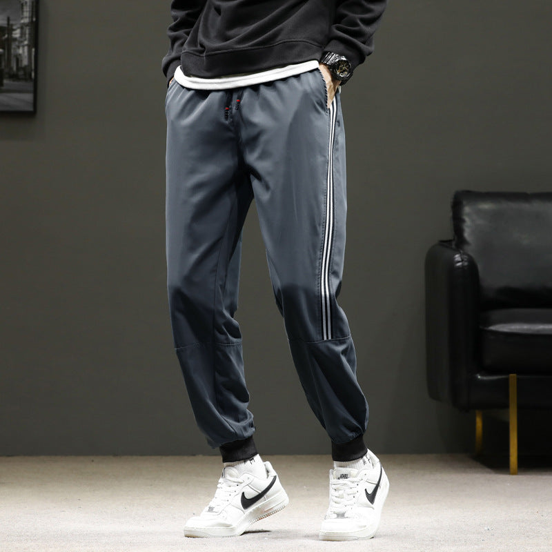 Men's sporty jogging pants in track style with side contrast stripes, drawstring, and elastic cuffs.