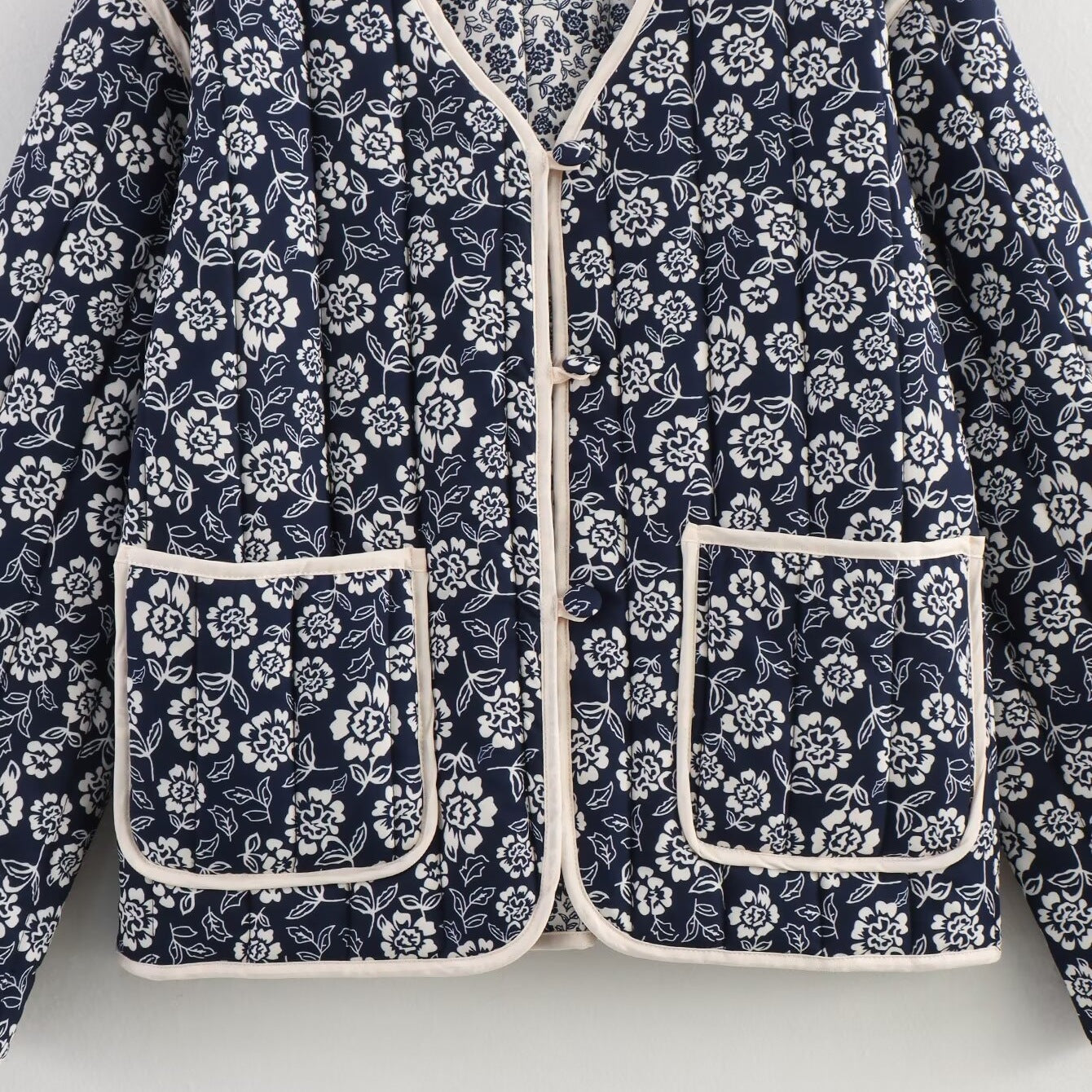 Ladies quilted jacket with floral allover, V-neck, contrast piping and patch pockets Chichicherry
