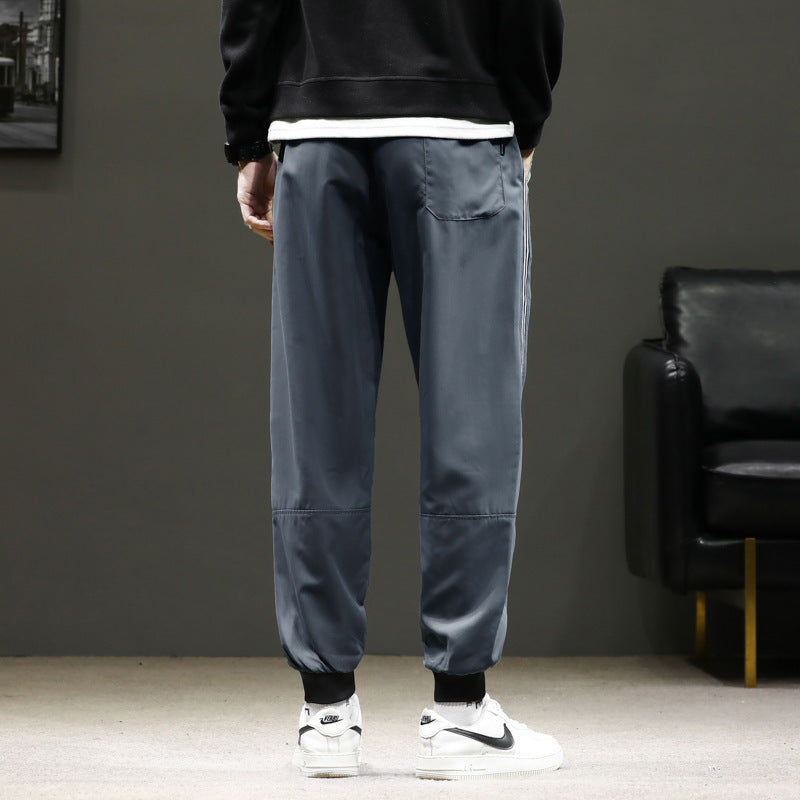 Men's sporty jogging pants in track style with side contrast stripes, drawstring, and elastic cuffs.