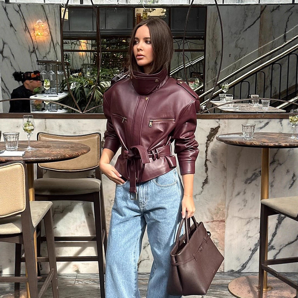 Women's short jacket made of faux leather with a high stand-up collar, fitted tie belt, and prominent shoulder pads Chichicherry