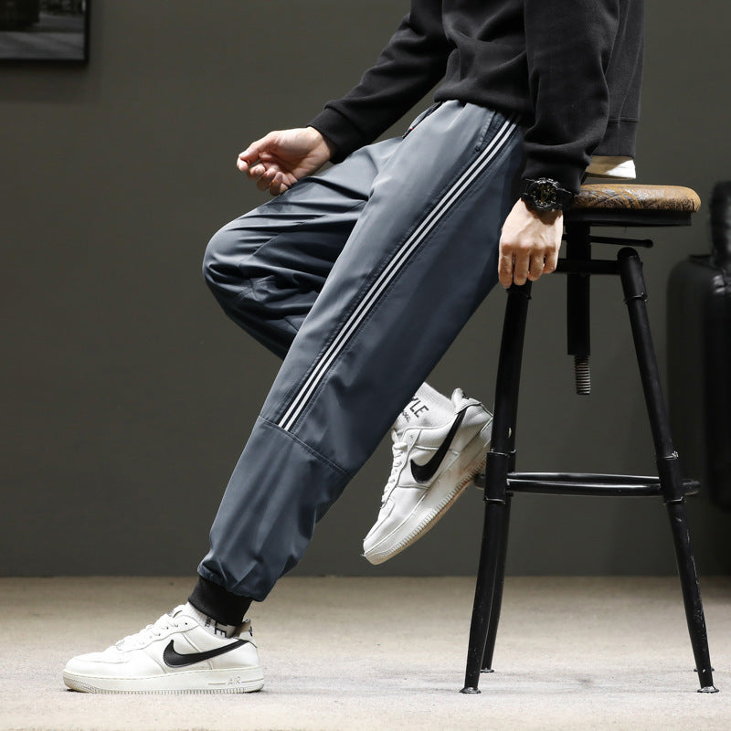 Men's sporty jogging pants in track style with side contrast stripes, drawstring, and elastic cuffs.