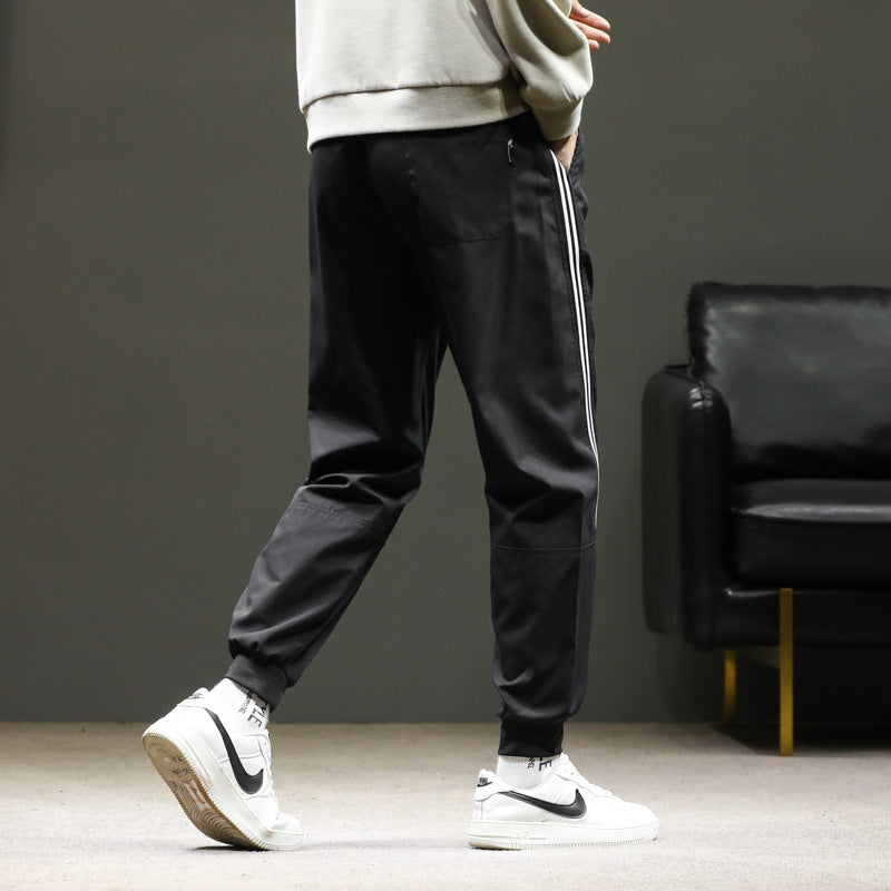 Men's sporty jogging pants in track style with side contrast stripes, drawstring, and elastic cuffs.