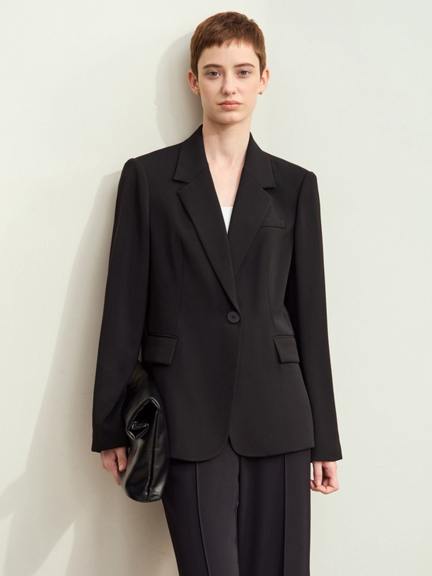 Model wearing black tailored blazer with notch lapels and relaxed fit