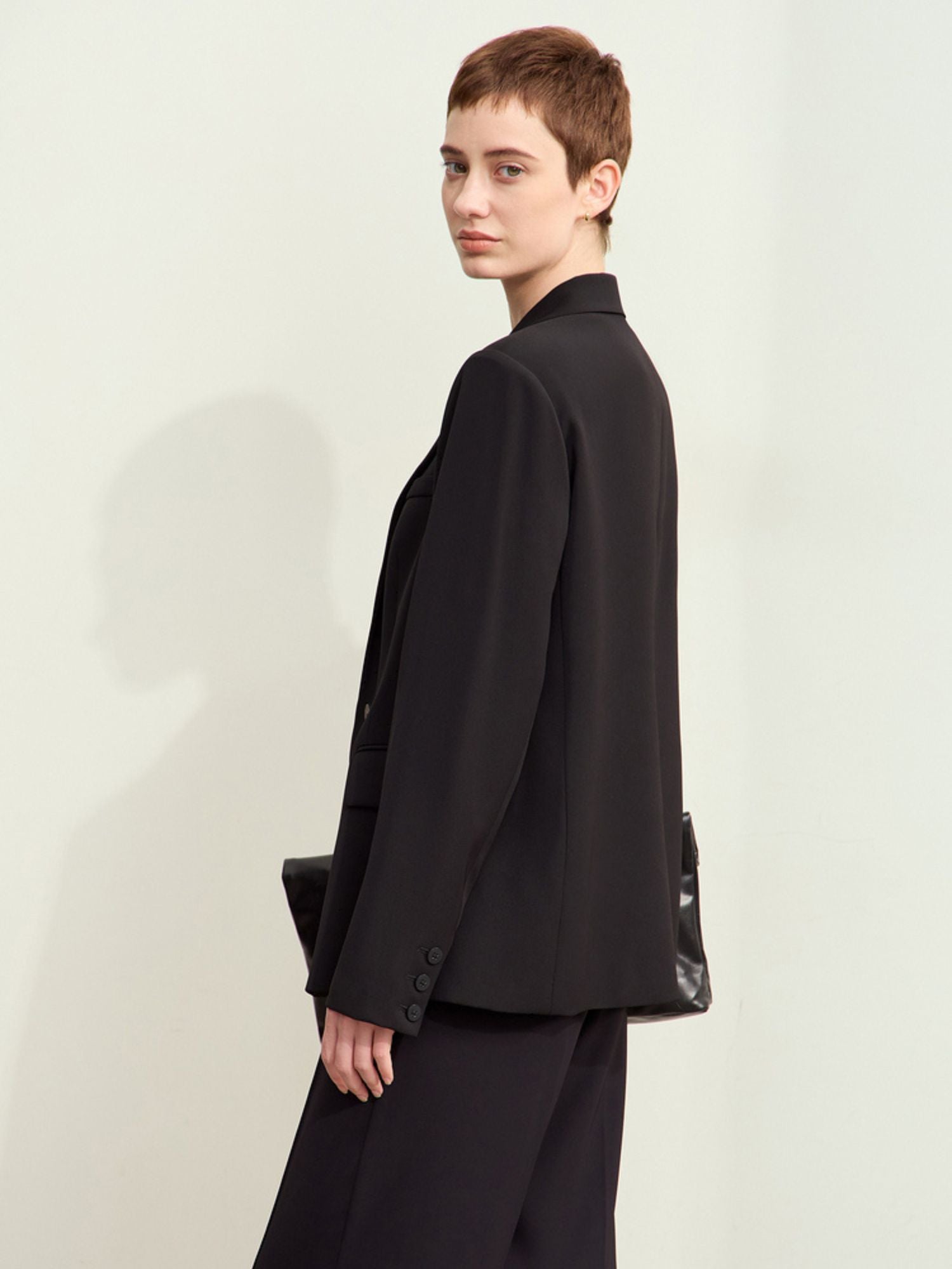 Three-quarter side/back view of black blazer paired with matching black trousers