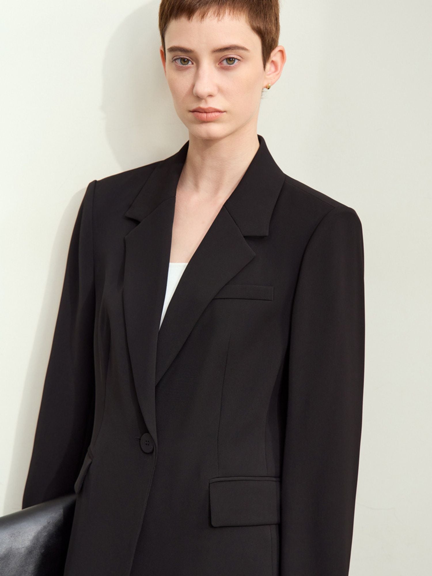 Detail close-up of the black blazer’s notch collar and double-breasted button closure
