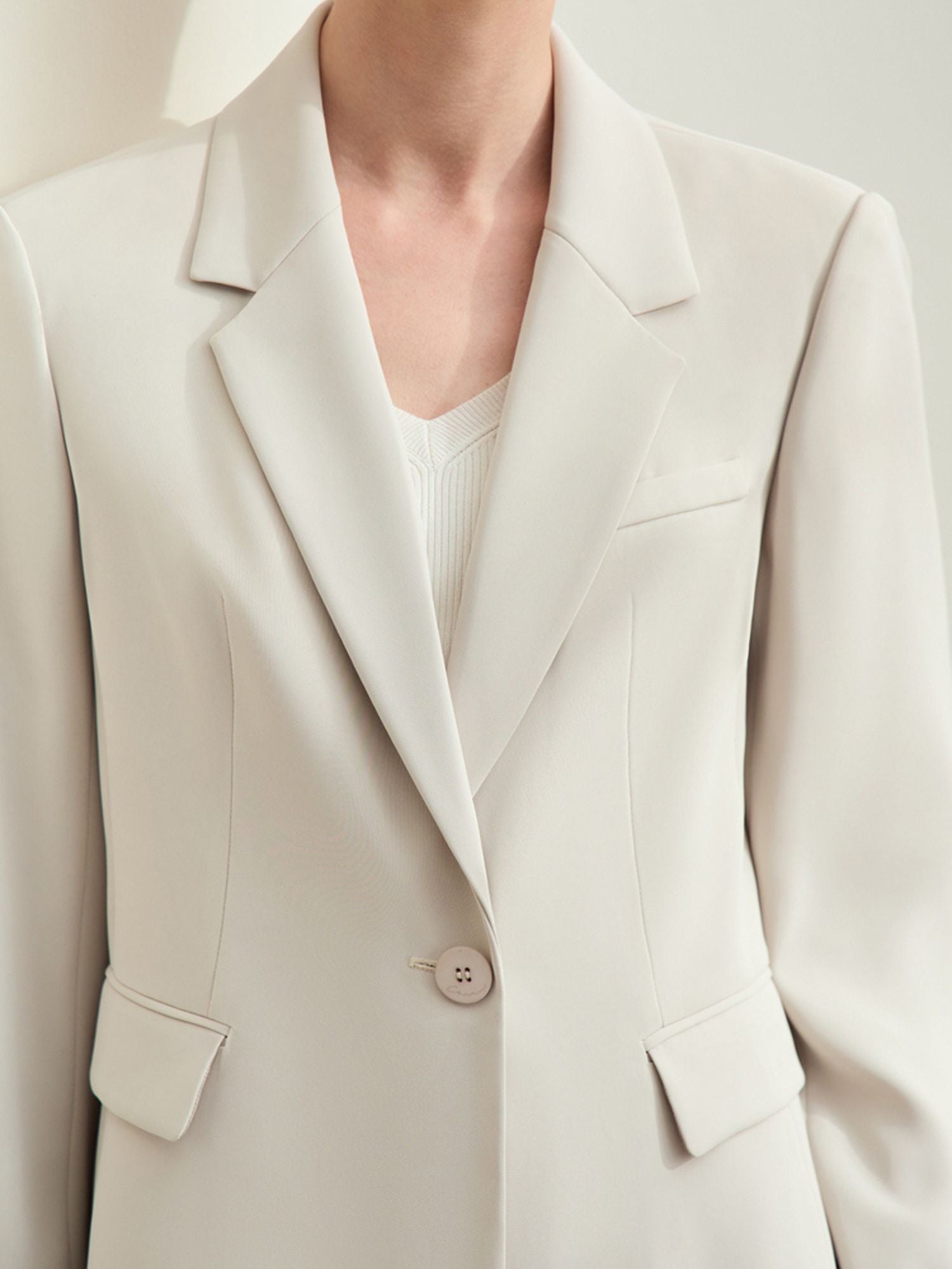 Detail close-up of the blazer’s notch collar and double-breasted button closure