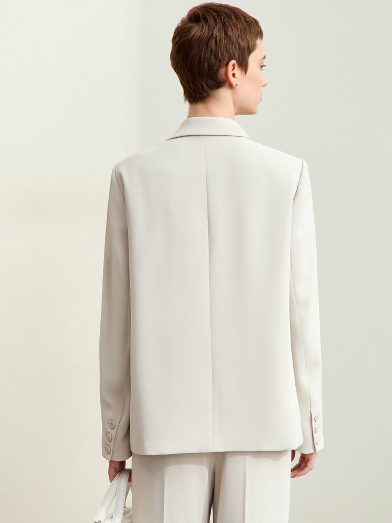 Back view of the cream blazer showing structured shoulders and center seam