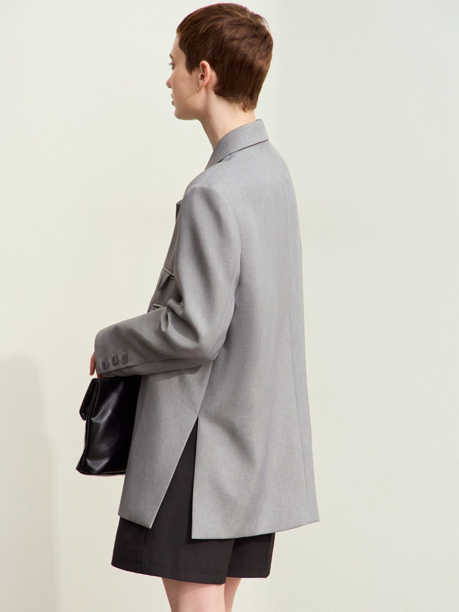 Close-up side view of light grey blazer flap pocket with subtle welt stitching