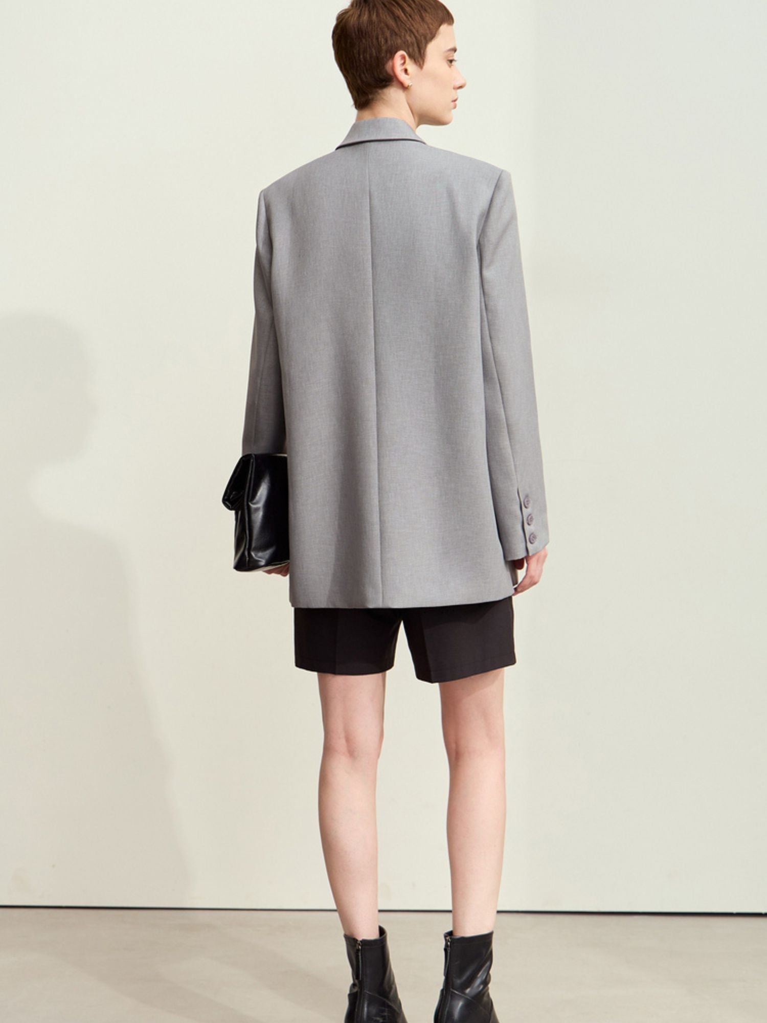 Back view of light grey oversized blazer paired with black shorts with relaxed fit