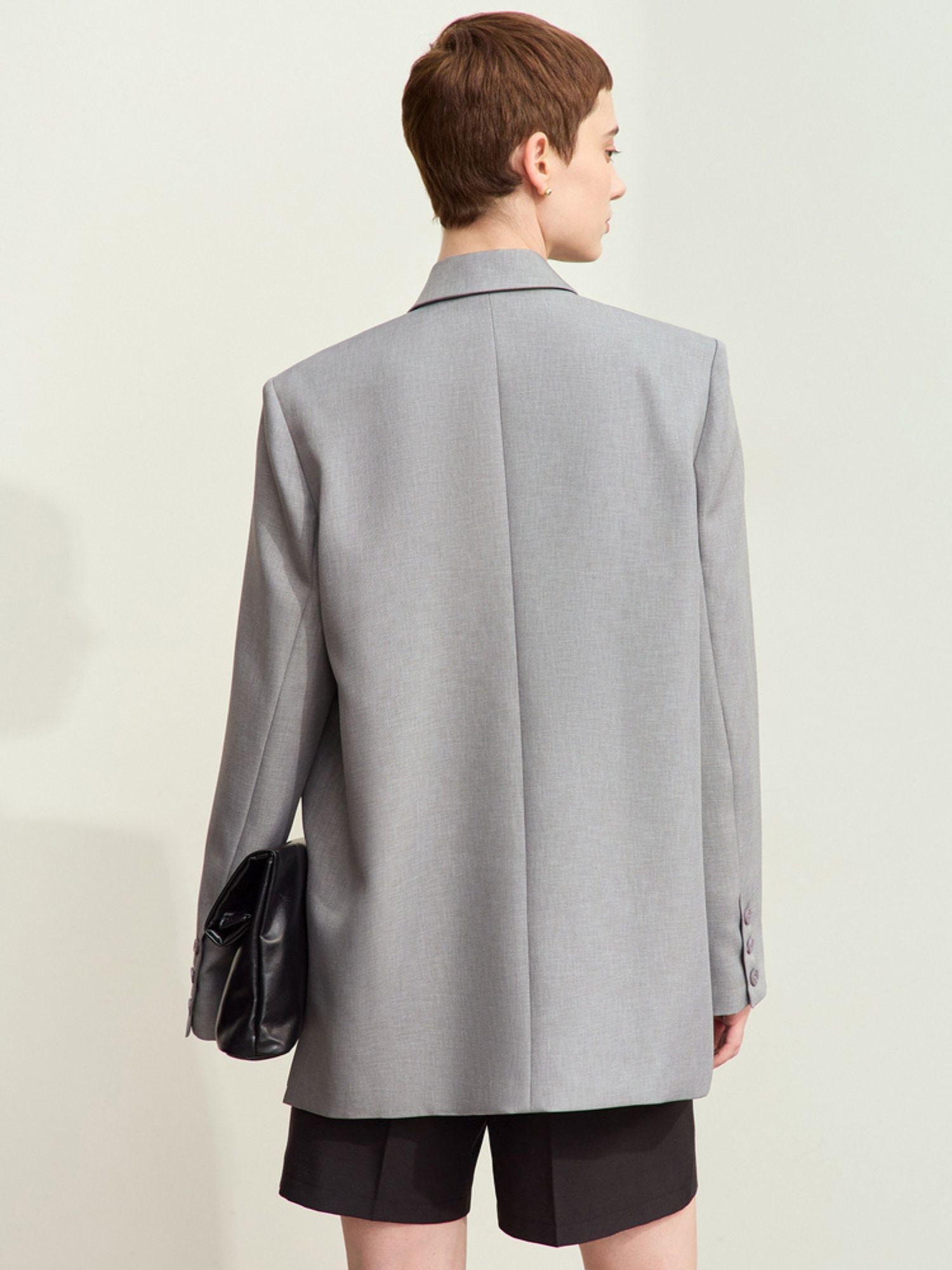 Detailed back view of light grey oversized blazer paired with black shorts