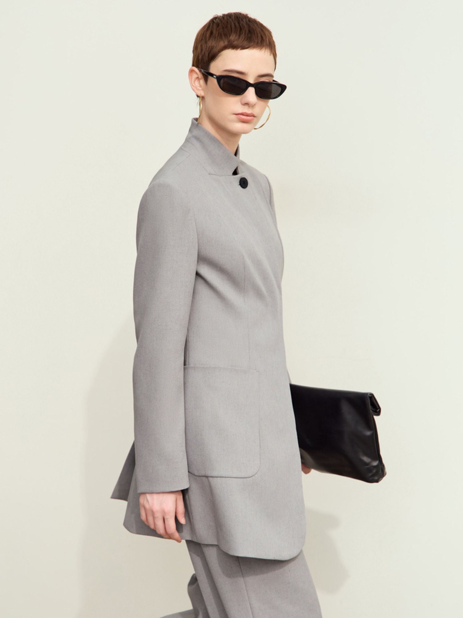 Model wearing light-grey blazer styled with tailored pants and sunglasses