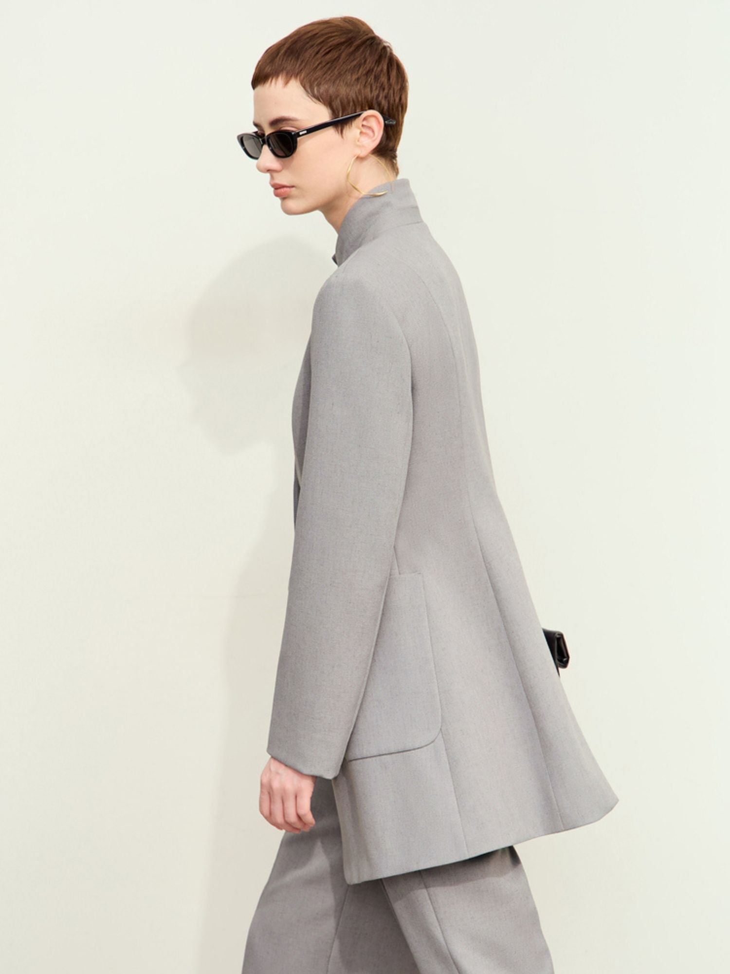 Three‑quarter side view of light-grey blazer highlighting tailored silhouette