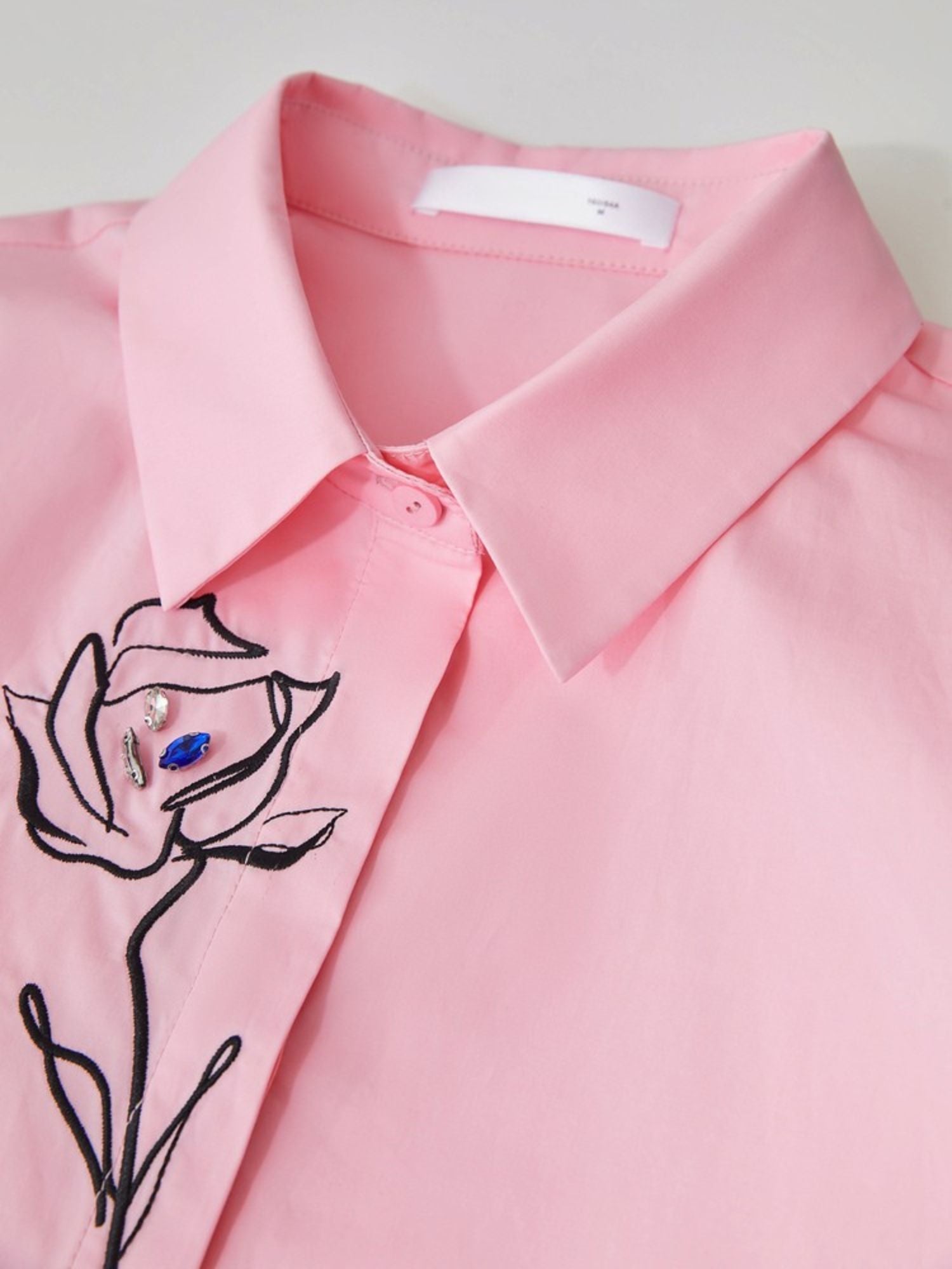 Front close-up of pink shirt highlighting rose embroidery and button closure