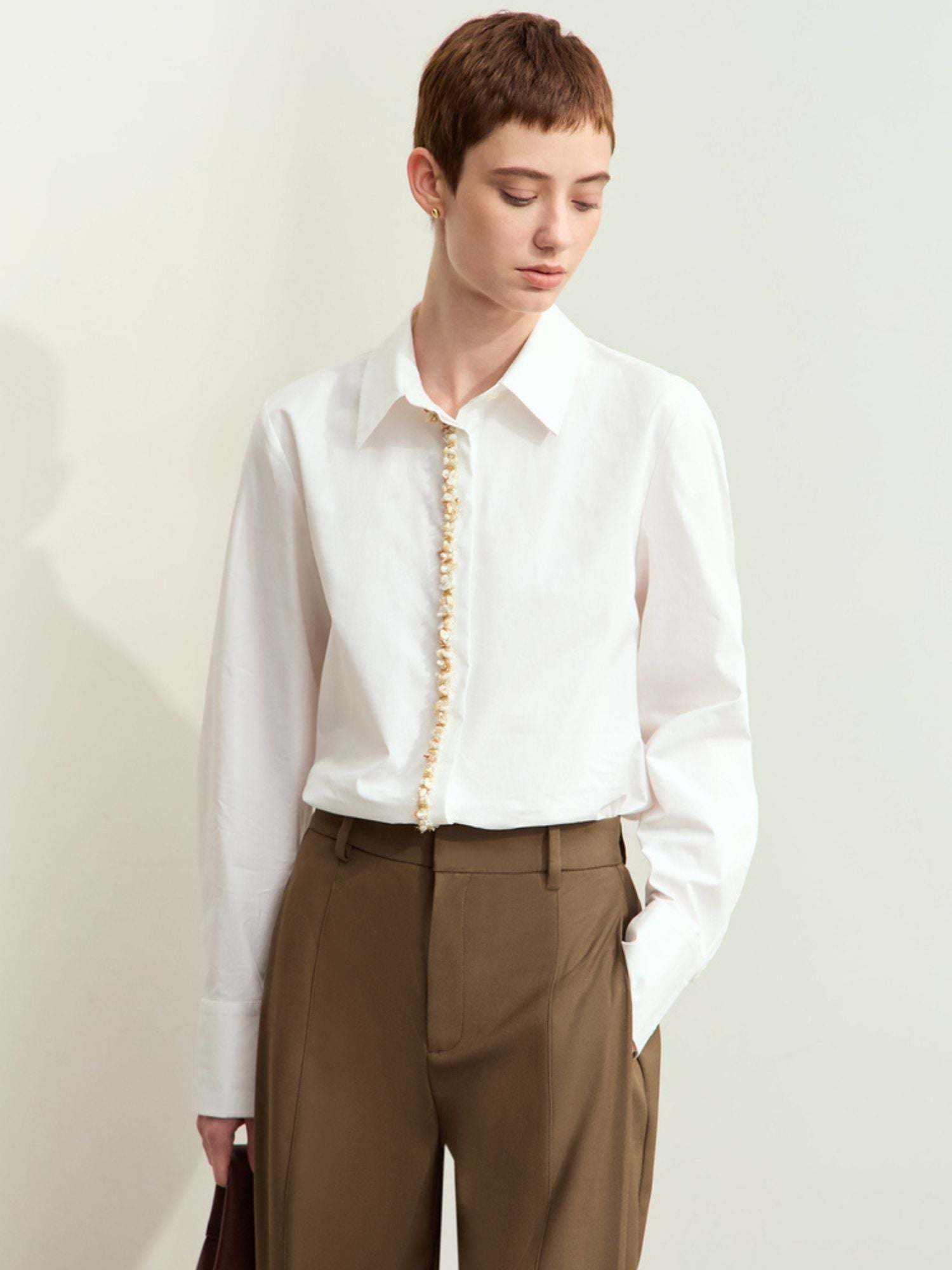 Model in white long-sleeve blouse with smooth texture and paired with trousers