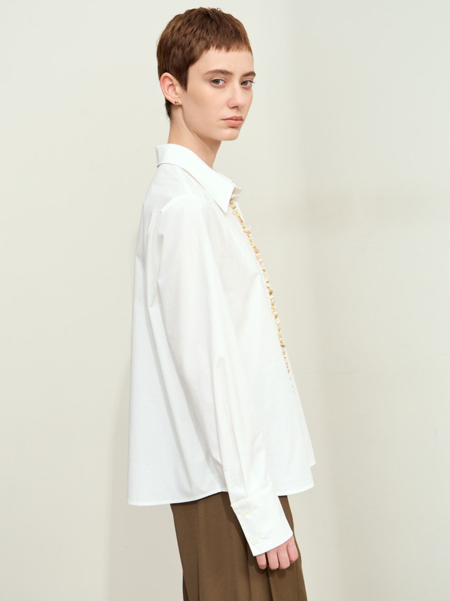 Side view of model in white long sleeves blouse paired with a trousers
