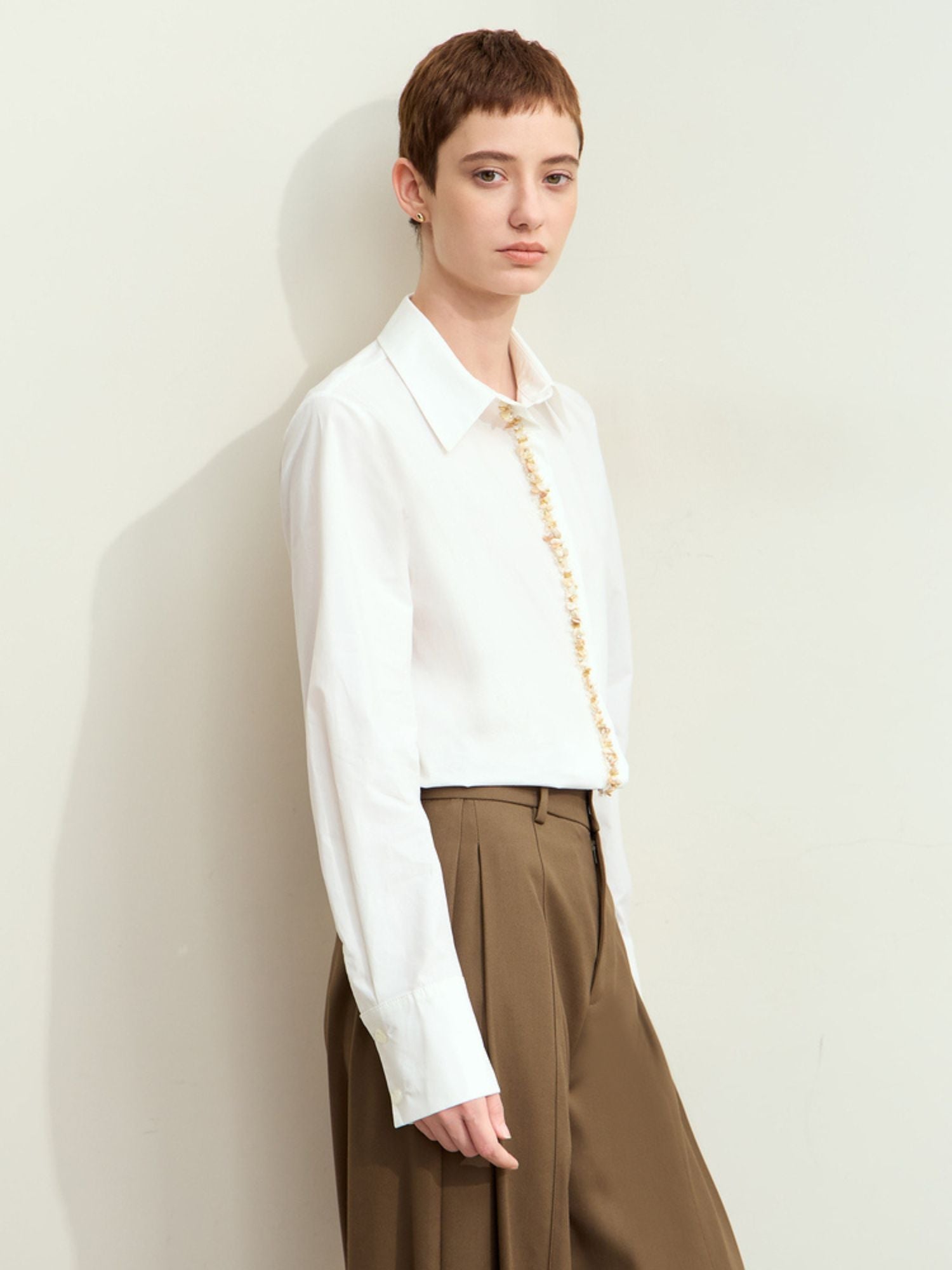 Three-quarter side view of model in white long sleeves blouse paired with a trousers