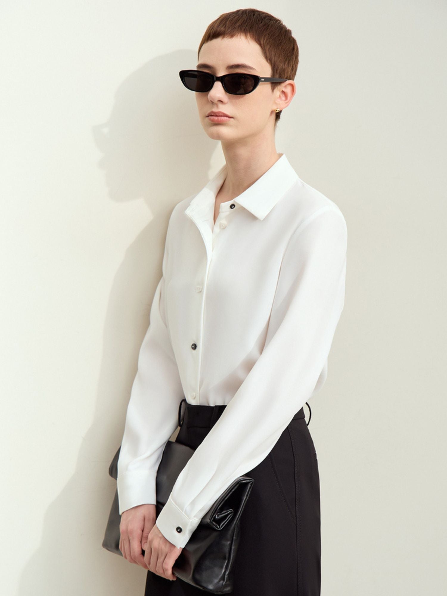 Side profile of white silk blouse and trousers, highlighting sleeve length and fit