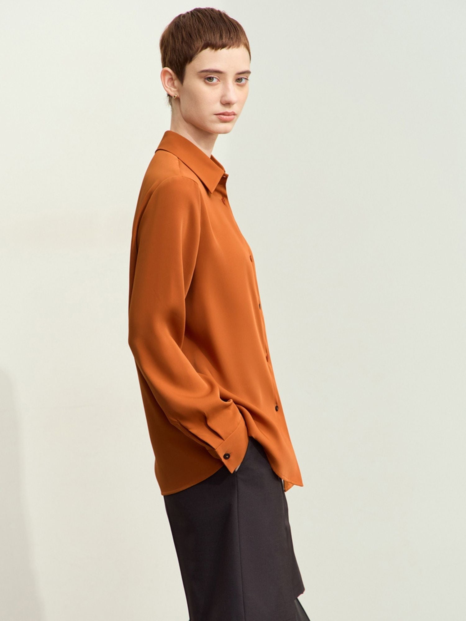 Three‑quarter side view of model in rust blouse highlighting sleeve fit and fabric texture