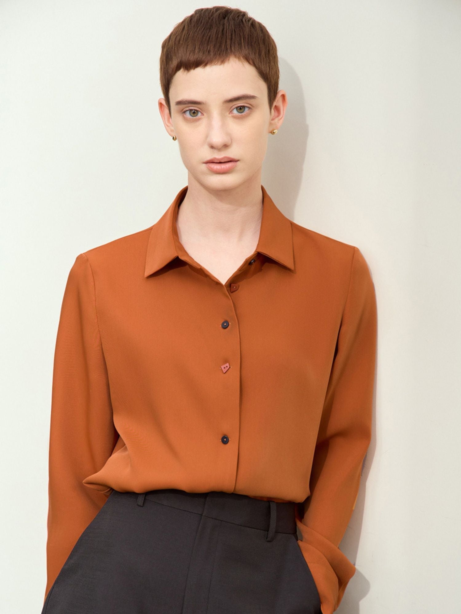 Front view of rust blouse tucked into black trousers, showing collar and button closures