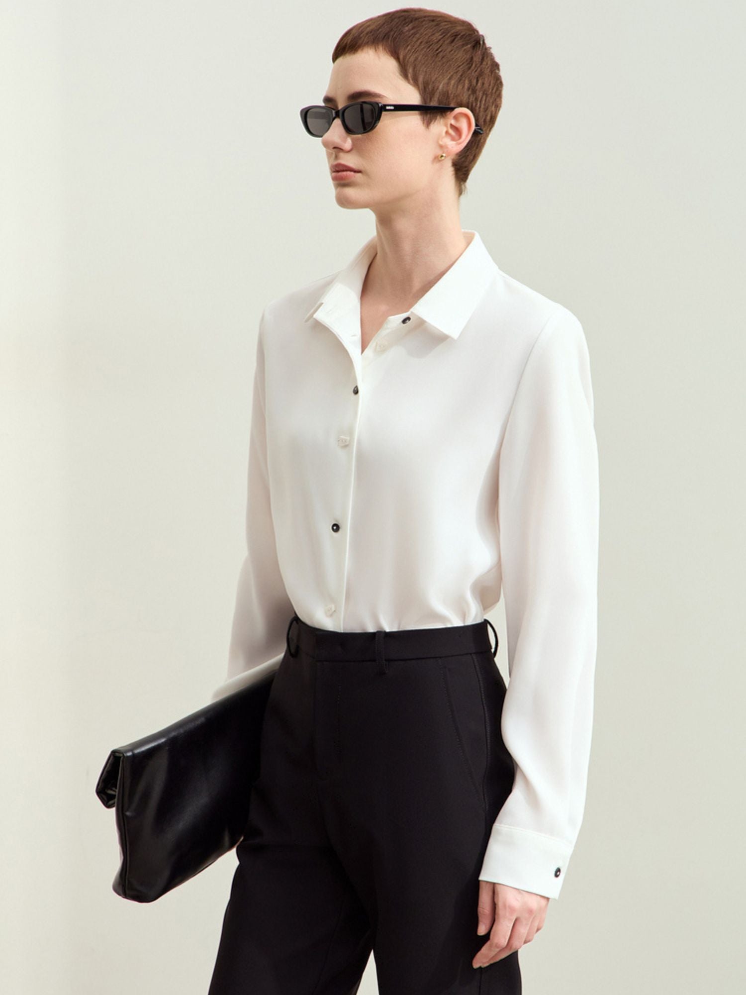 Model in white silk blouse and black trousers, side profile view showing smooth drape