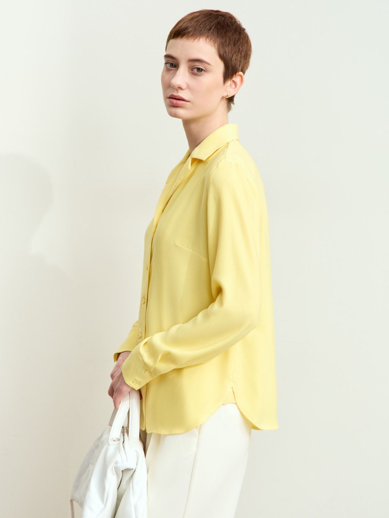 Side view of model in yellow silk blouse and white trousers, smooth drape visible