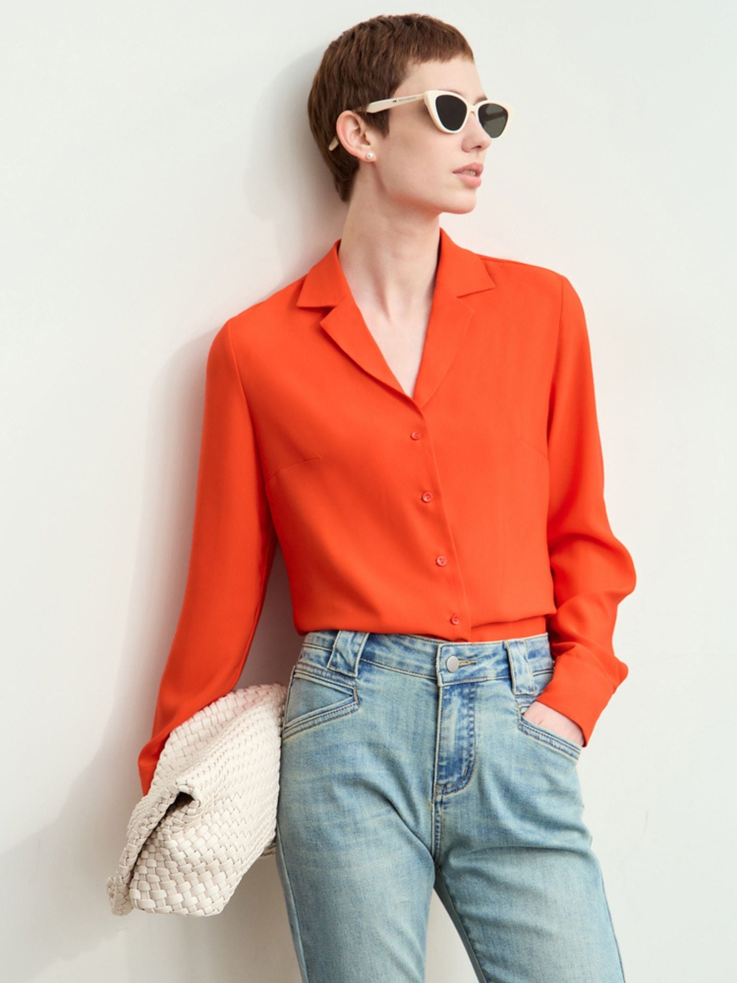 Model wearing rust-orange silk blouse with pointed collar tucked into her jeans