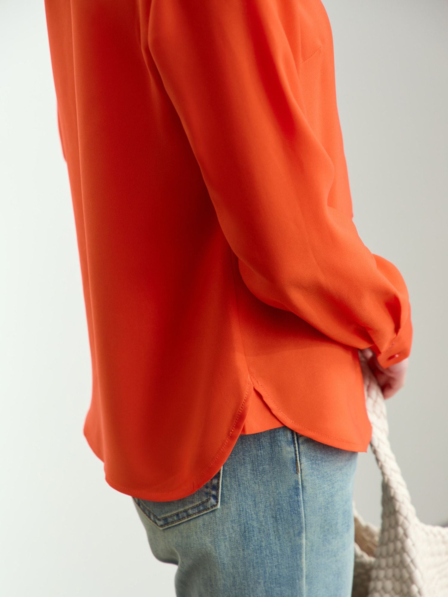 Side profile of rust silk blouse paired with a pair of jeans