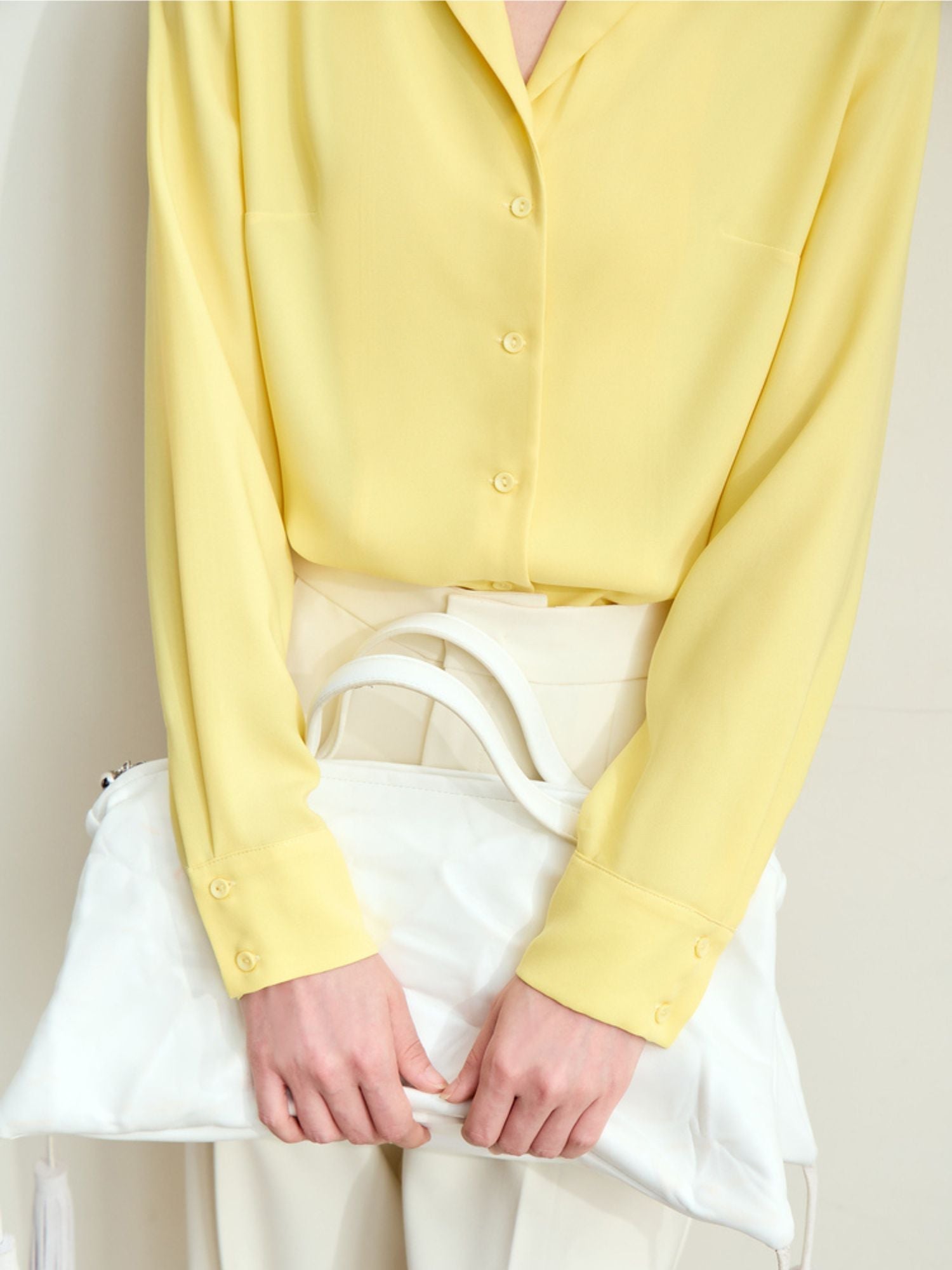 Close-up detail of yellow blouse’s, and model styled it with a white bag