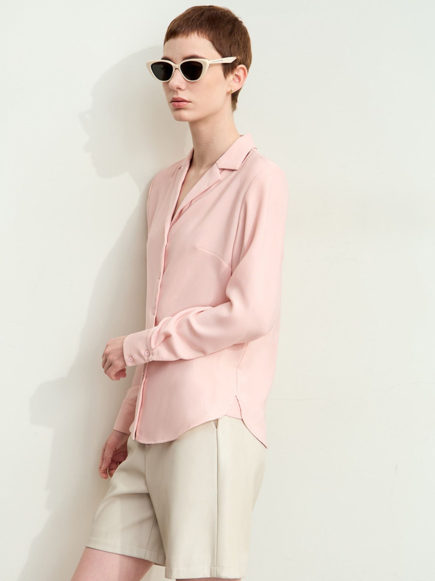 Side view of model in pink silk blouse and shorts, smooth drape visible