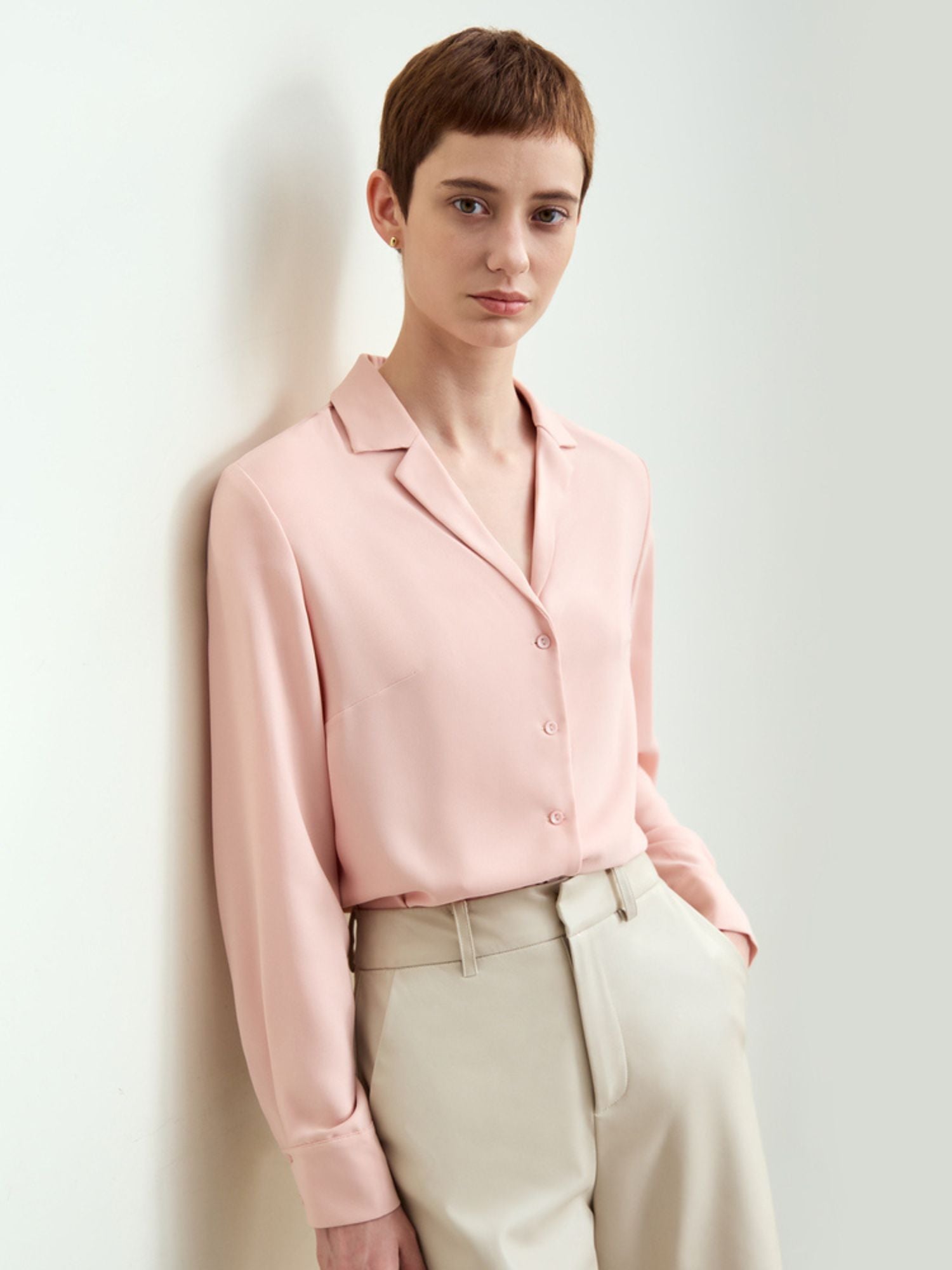 Model wearing pink silk blouse and cream beige trousers