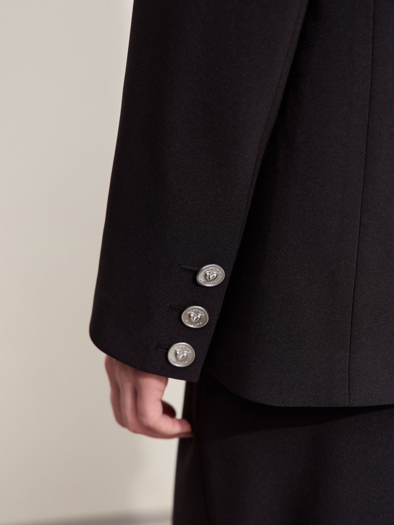 Close-up of silver buttons on the sleeve cuff of the black blazer