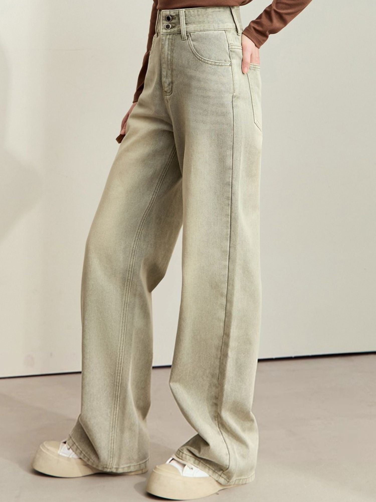 Three-quarter front view of light-wash wide-leg jeans paired with a brown top and white shoes
