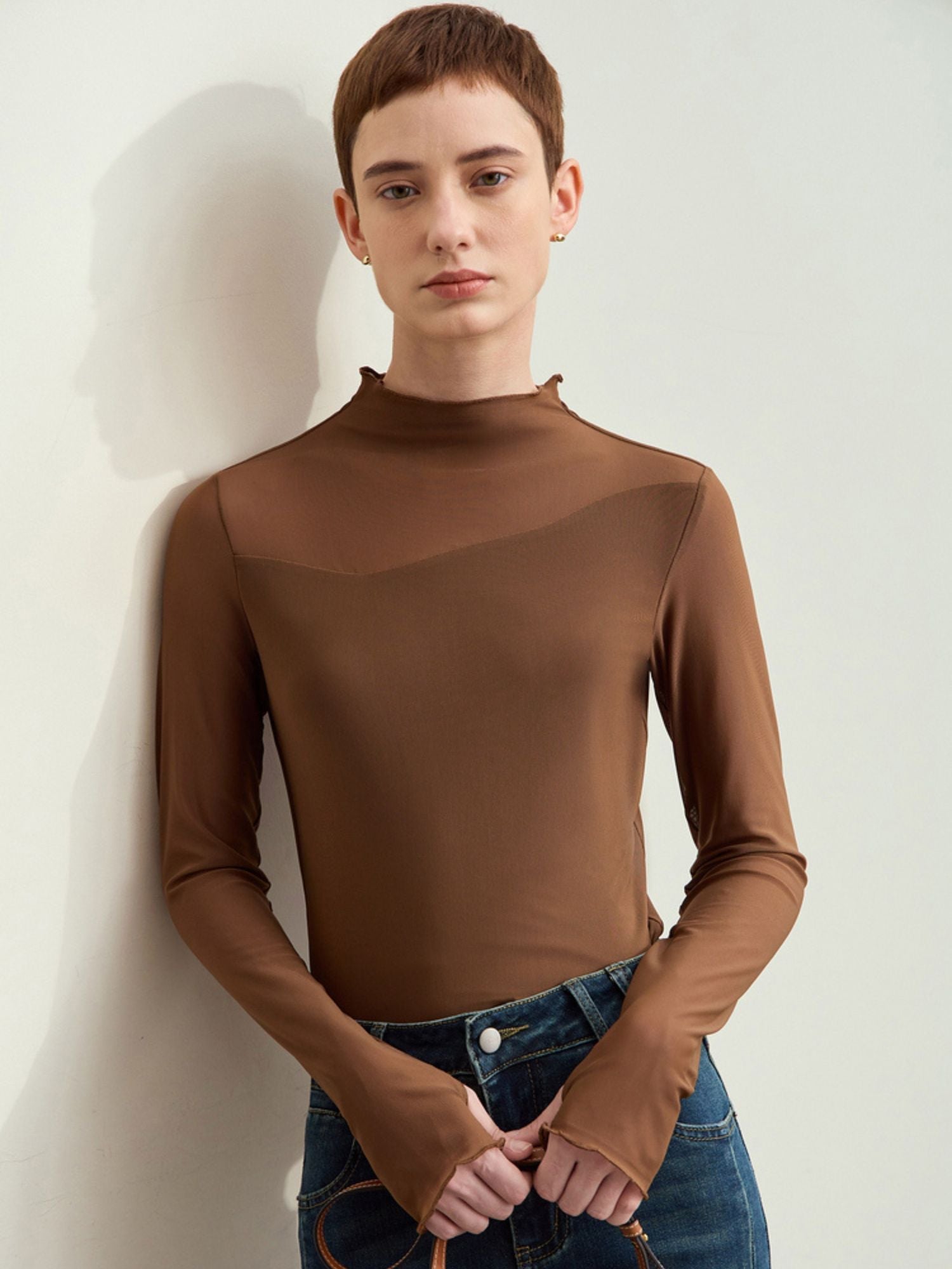 Model in brown long-sleeve blouse with smooth texture and round neckline paired with jeans