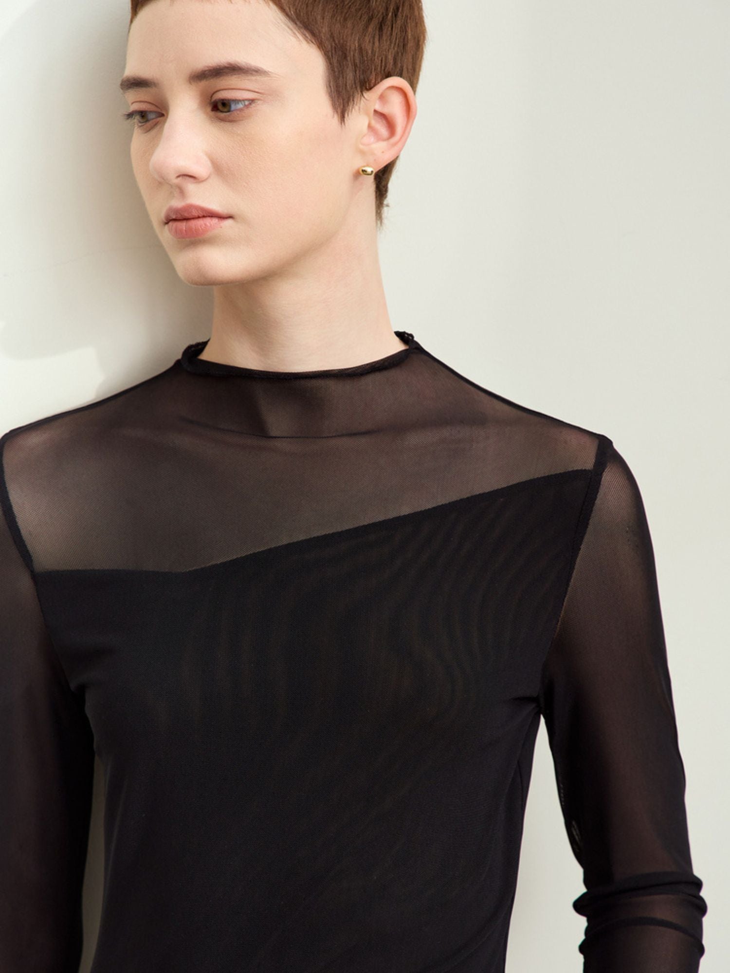 Close-up front view of a model wearing sheer black long-sleeve blouse with mesh shoulders