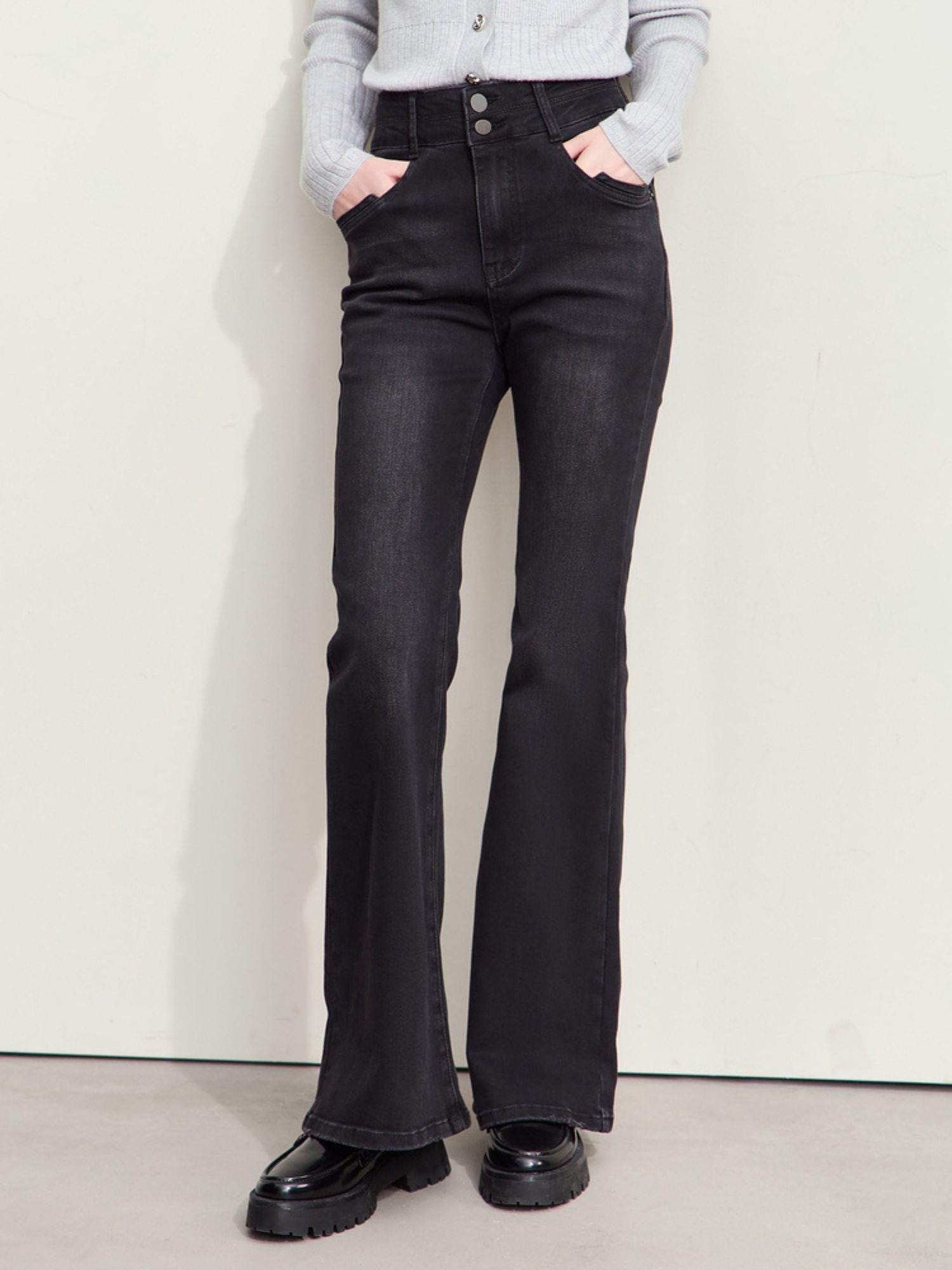 Front view of a person wearing high-waisted, flared black jeans paired with black shoes