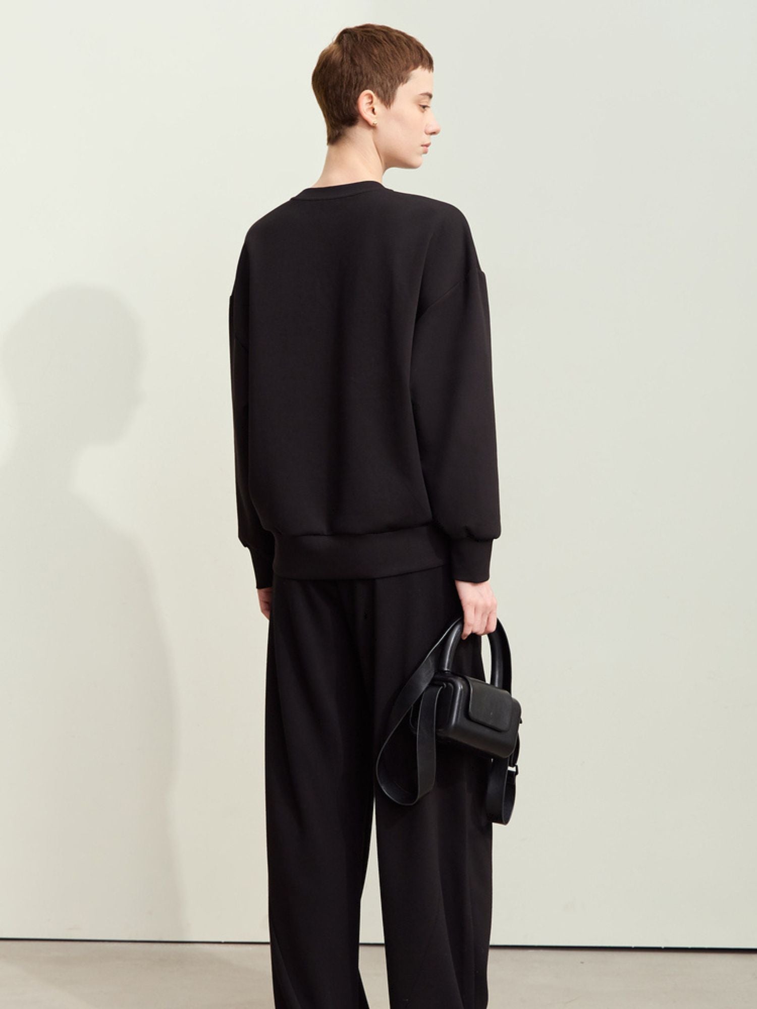 Rear view of black graphic sweatshirt showcasing clean silhouette and long sleeves