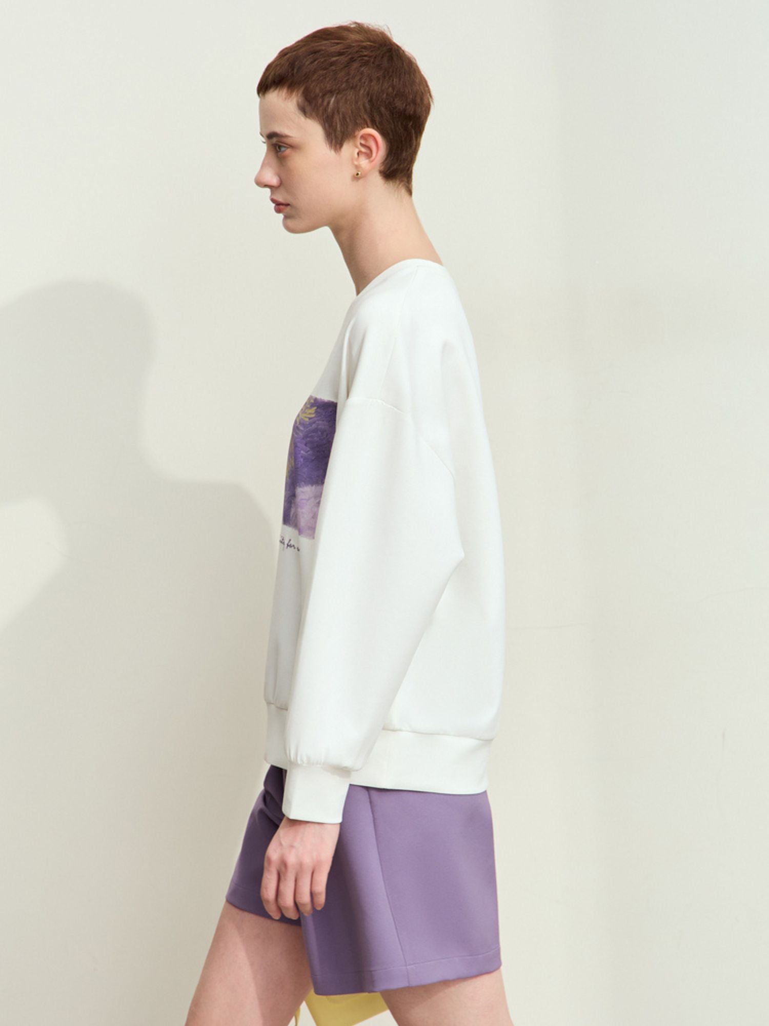 Side/back view of white sweatshirt and lavender shorts highlighting graphic placement and drape