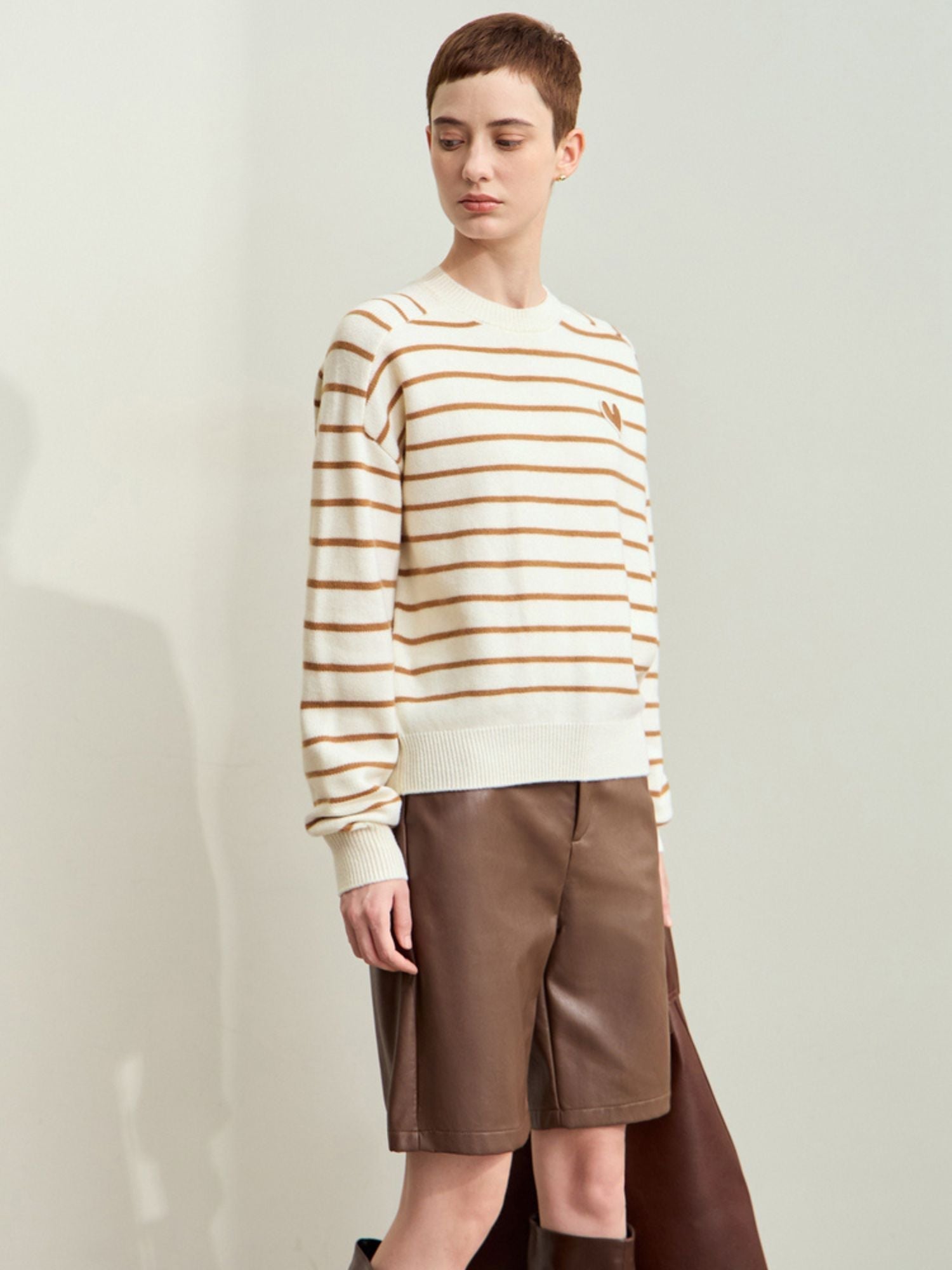 Full front view of model wearing beige striped sweater paired with brown shorts
