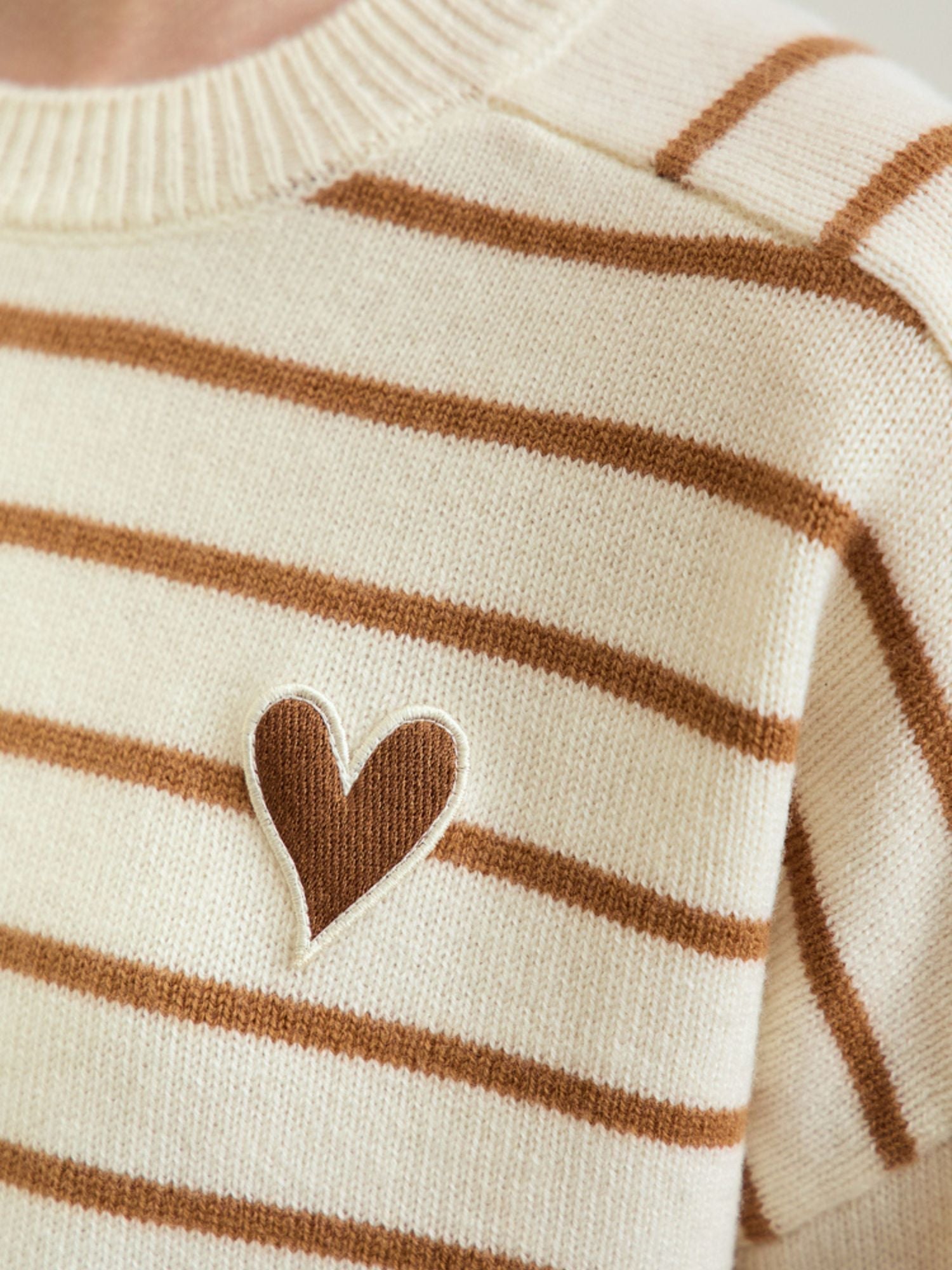 Close-up detail of the heart motif label on the striped sweater