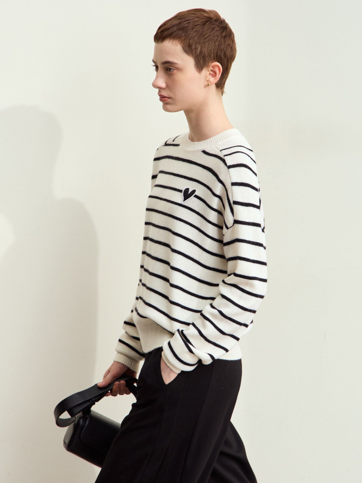 Side view of model in black-striped sweater, showing side fit