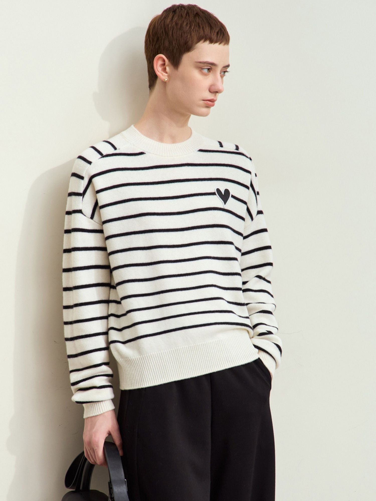 Full front view of model wearing a striped sweater paired with black pants