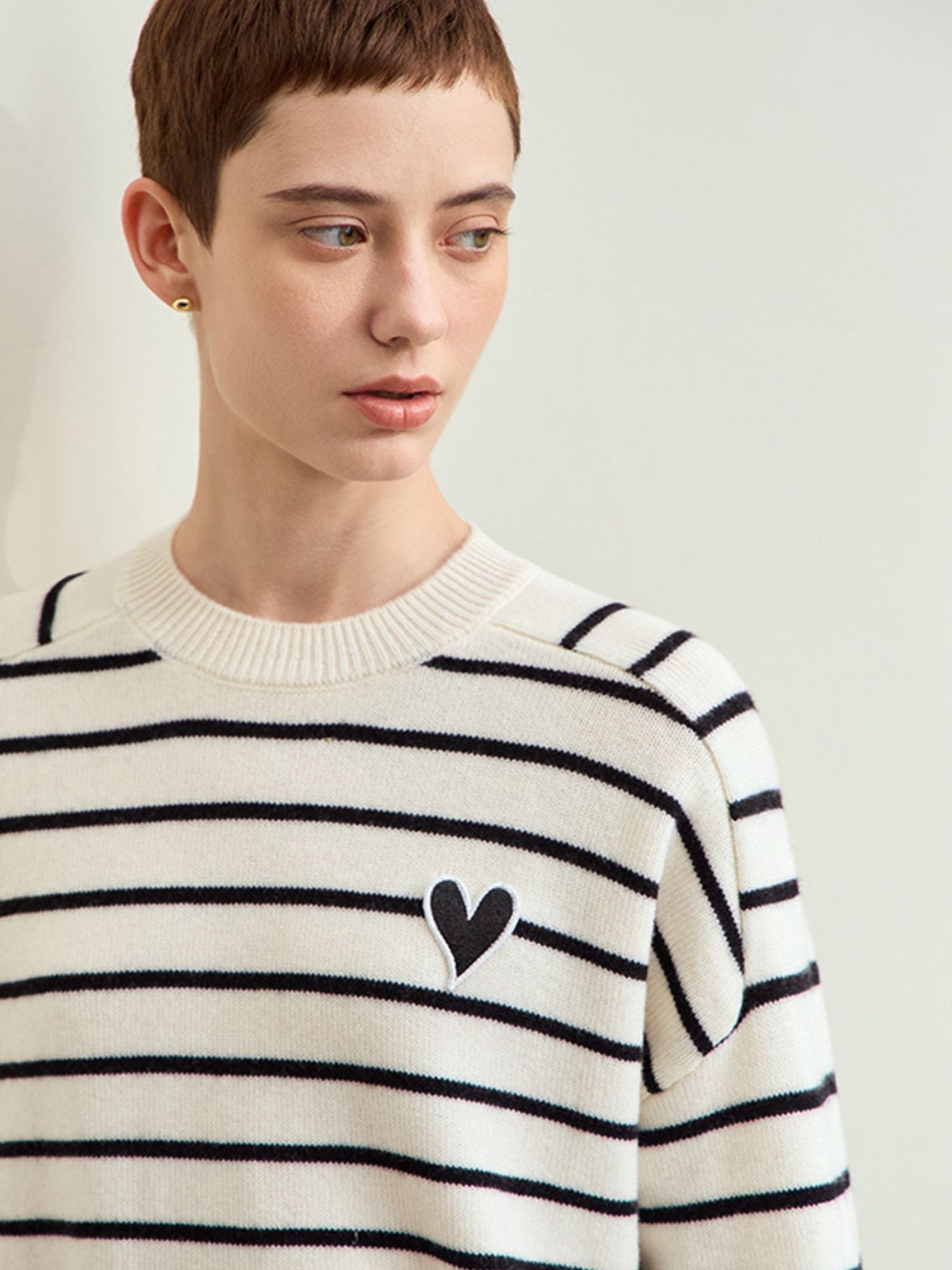 Close-up detail of the black heart motif label on the striped sweater