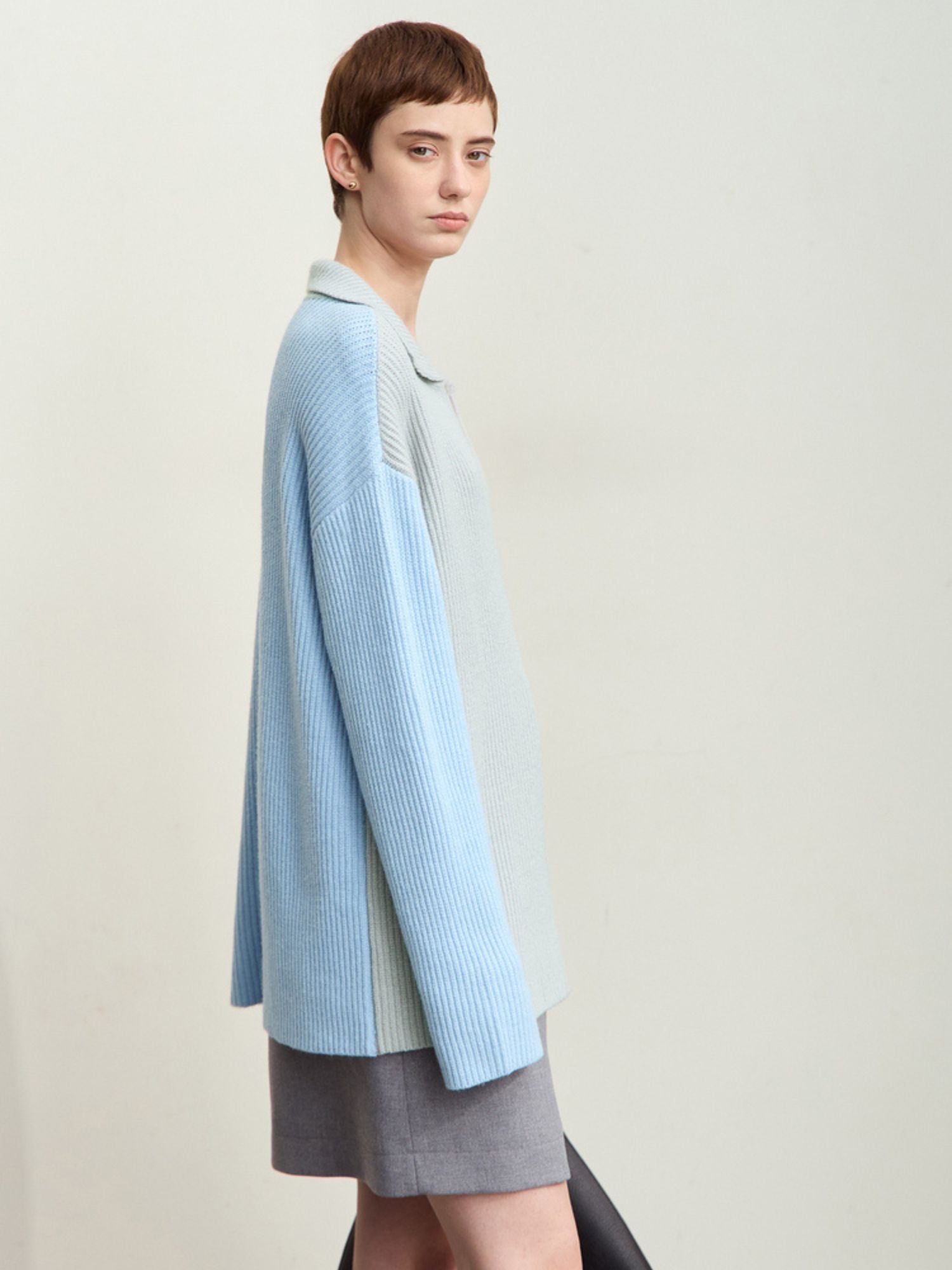 Three-quarter front view of model wearing the sweater paired with a skirt, standing facing right