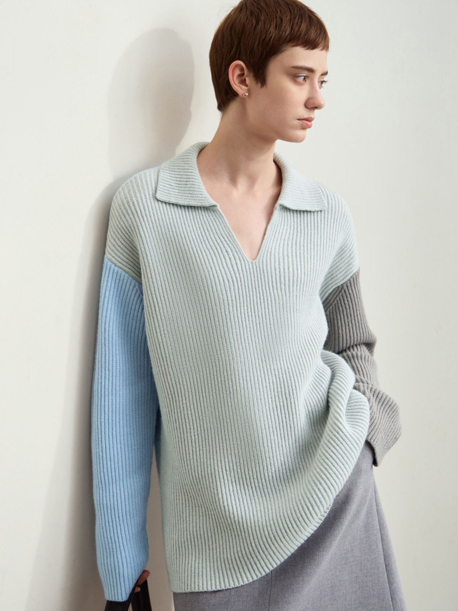 Side view of model in same color-block sweater, showing light blue sleeve and knit texture