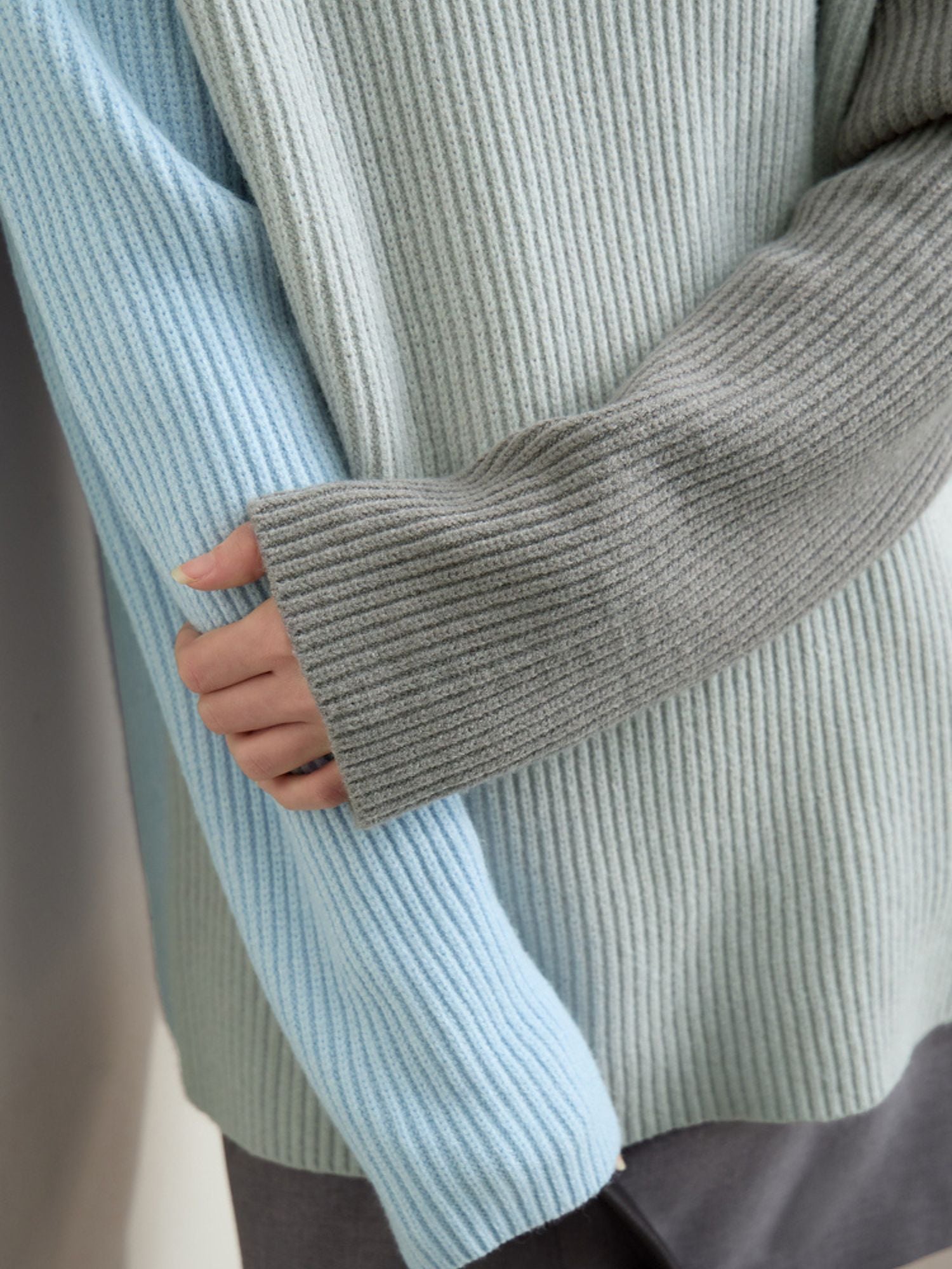 Side profile of model in sweater highlighted by grey and mint sleeves